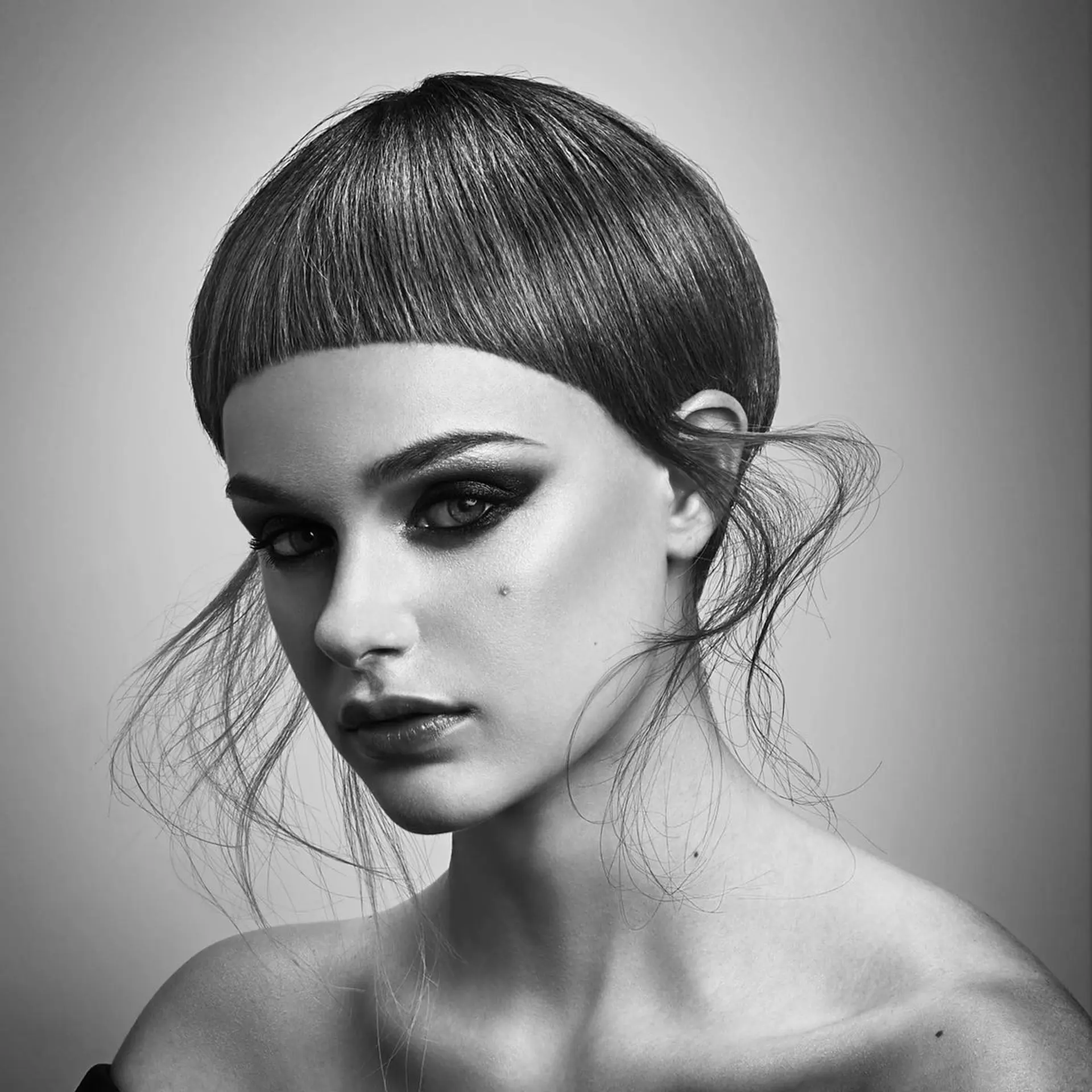 A precision-crafted bowl cut featuring sharp micro bangs paired with delicate, sculpted wispy tendrils flaring at the sides. 1