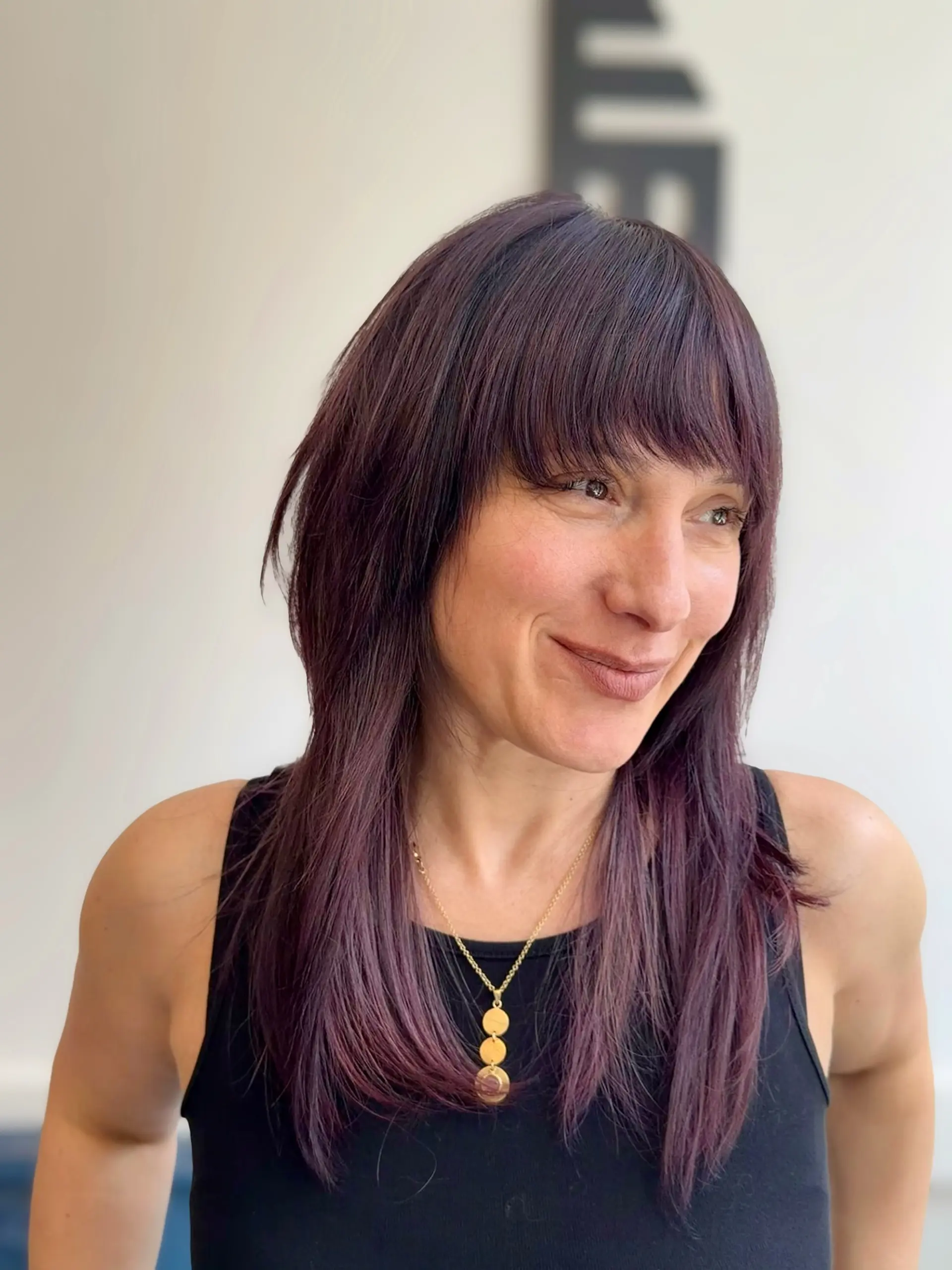 Long dark plum shag cut with full, straight fringe bangs. 1