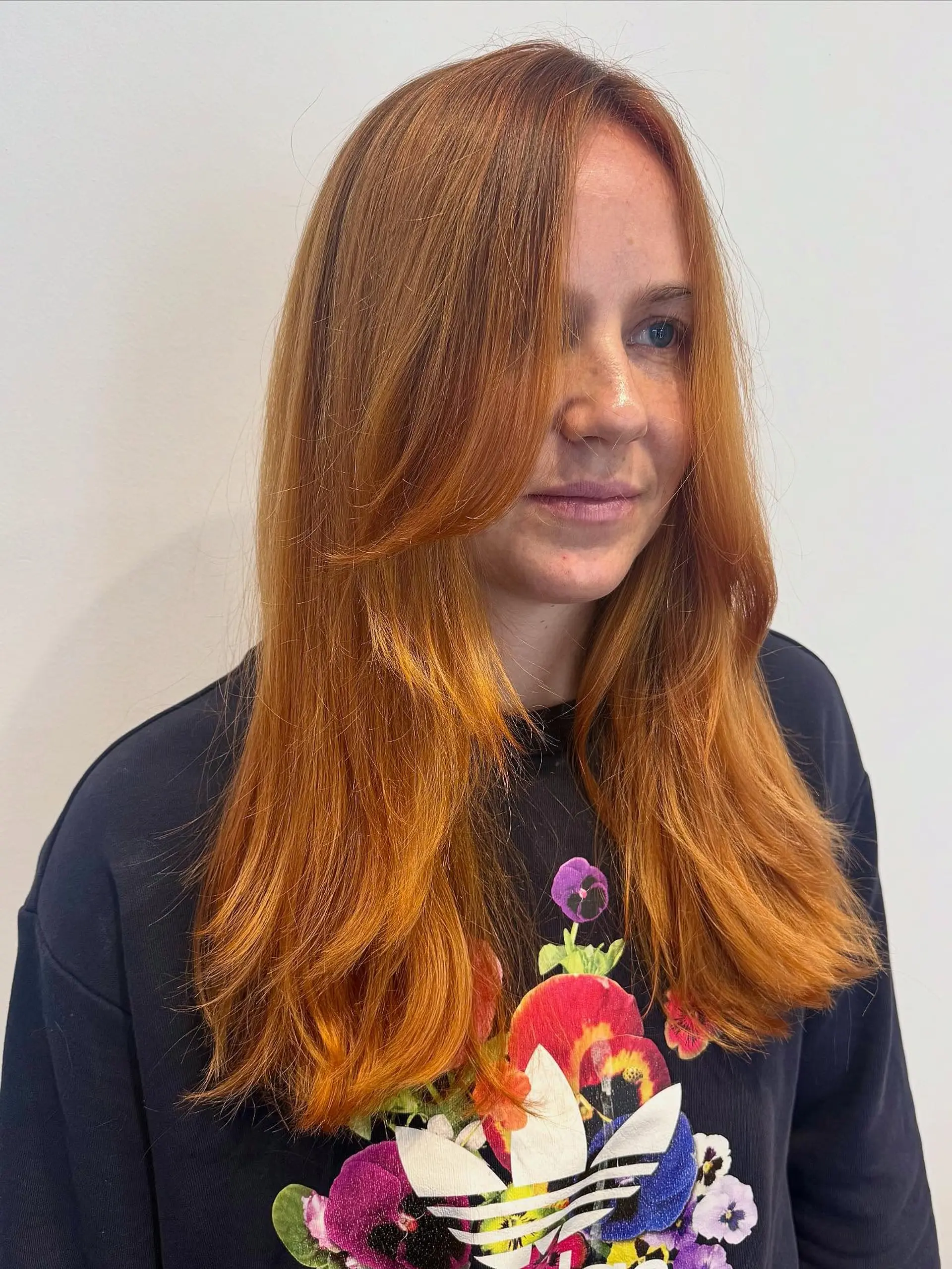 Vibrant copper-toned long hair featuring face-framing layers and sweeping curtain bangs. 1