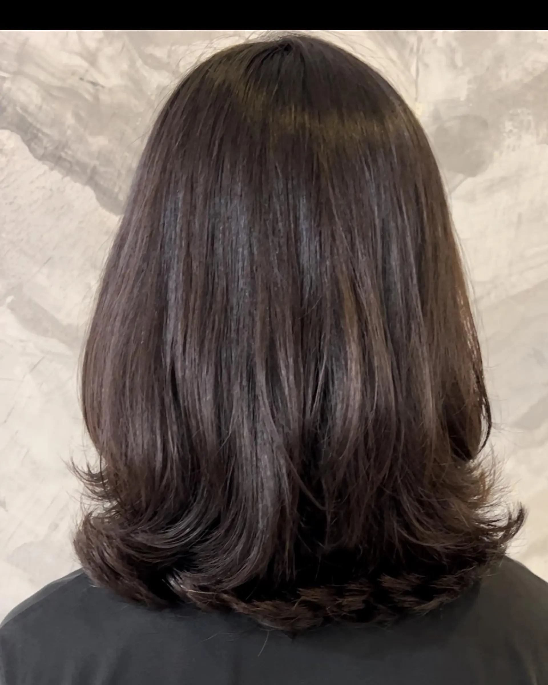 Medium-length layered dark hair featuring smooth, straight lengths with outwardly flipped C-curled ends. 1