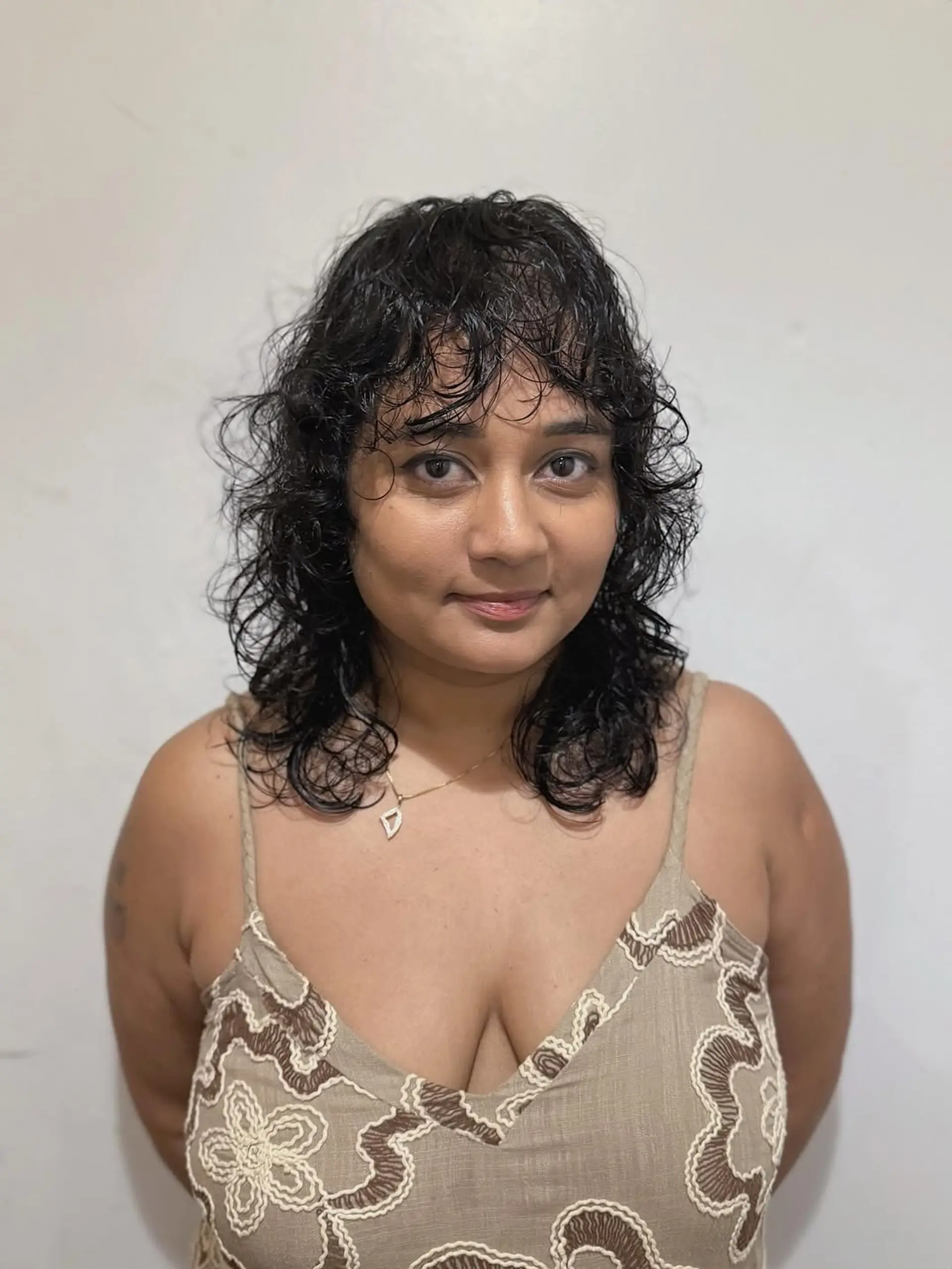 This medium-length shag cut is designed with numerous layers to enhance natural waves and curls, creating volume and movement. It is perfectly complemented by soft, curly bangs that gently frame the face. 1