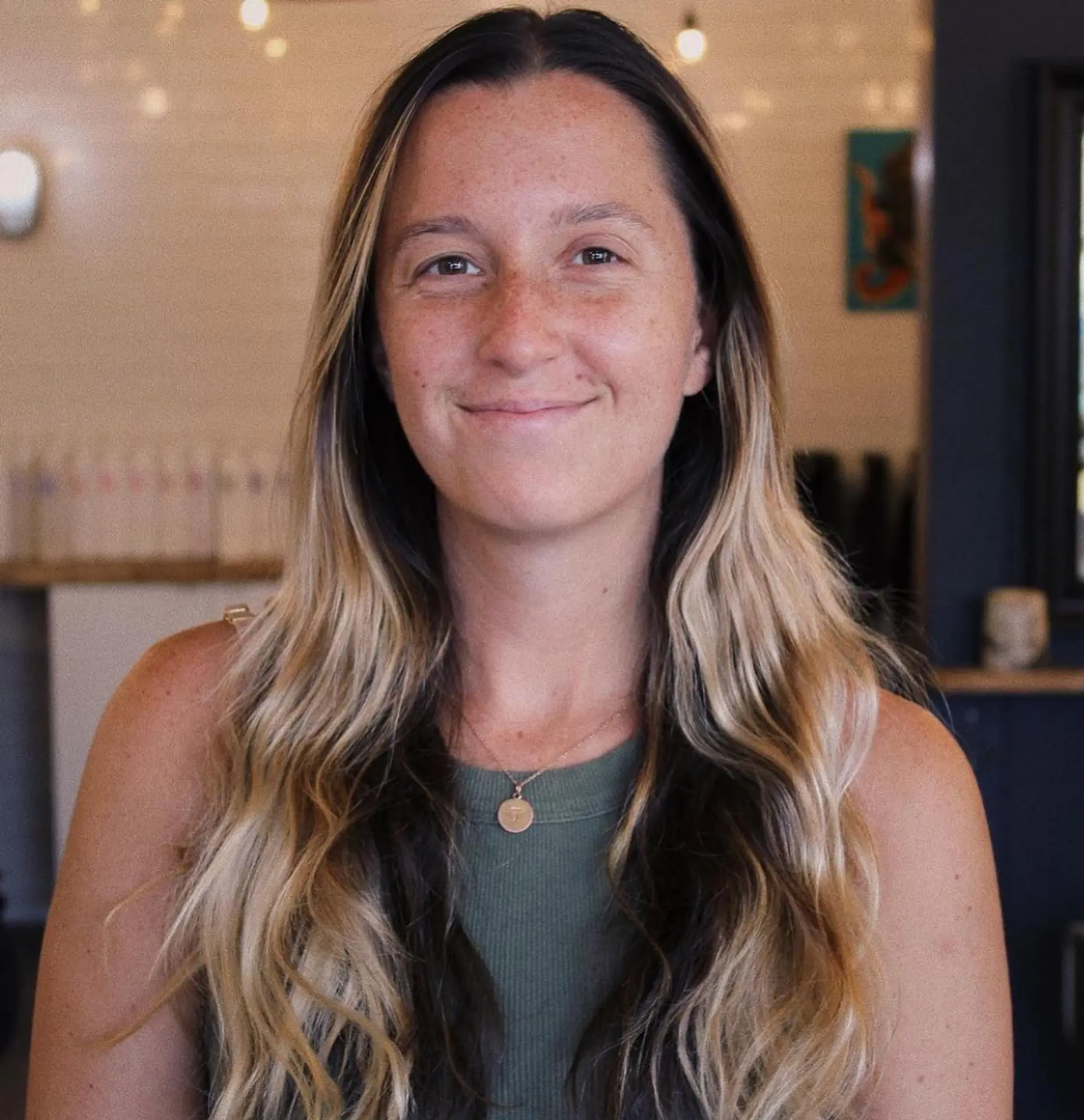 Long dark hair seamlessly blended into soft blonde balayage highlights with relaxed, loose waves. 1