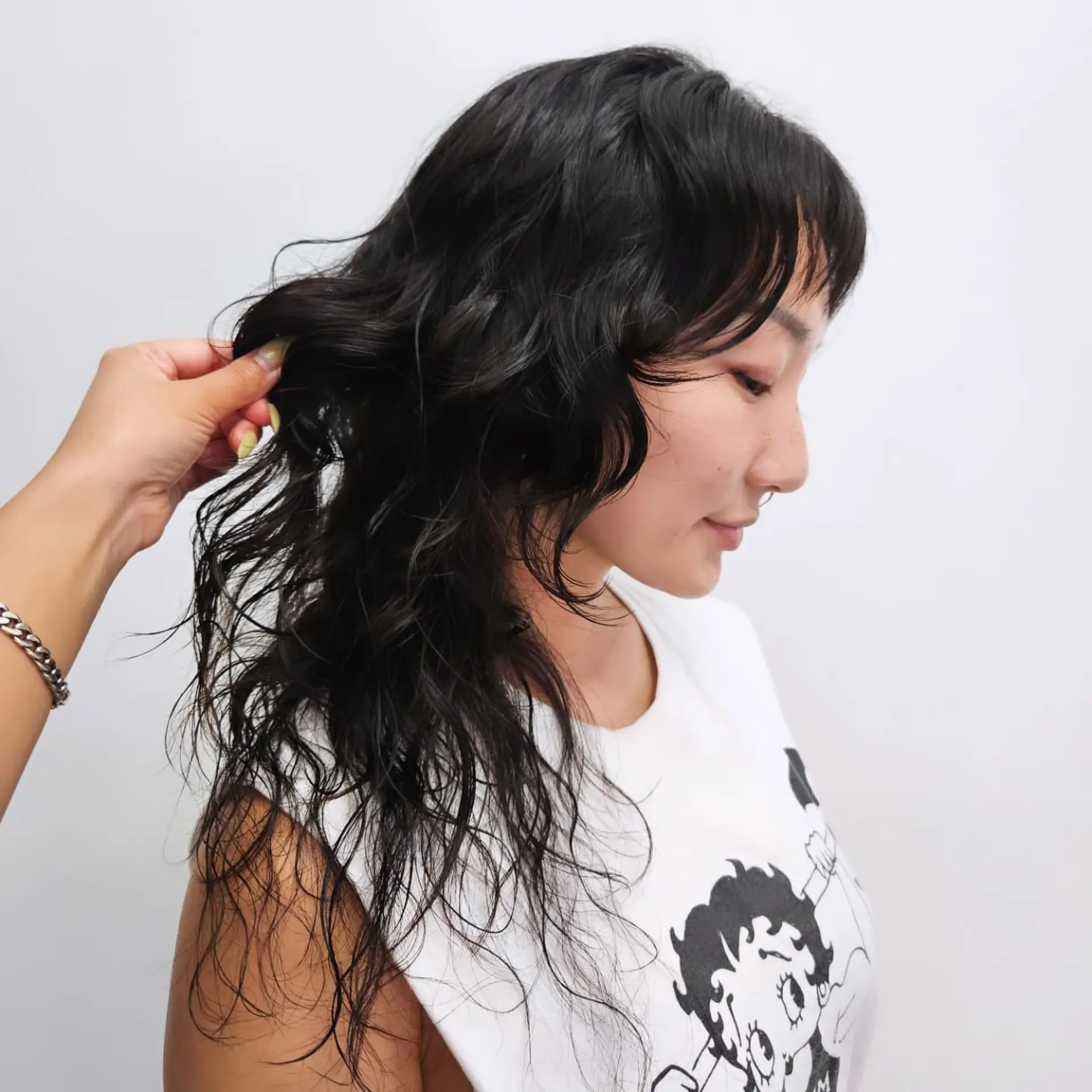 A soft, textured shaggy mullet haircut featuring piecey waves, micro fringe bangs, and long layered lengths in natural black. 1