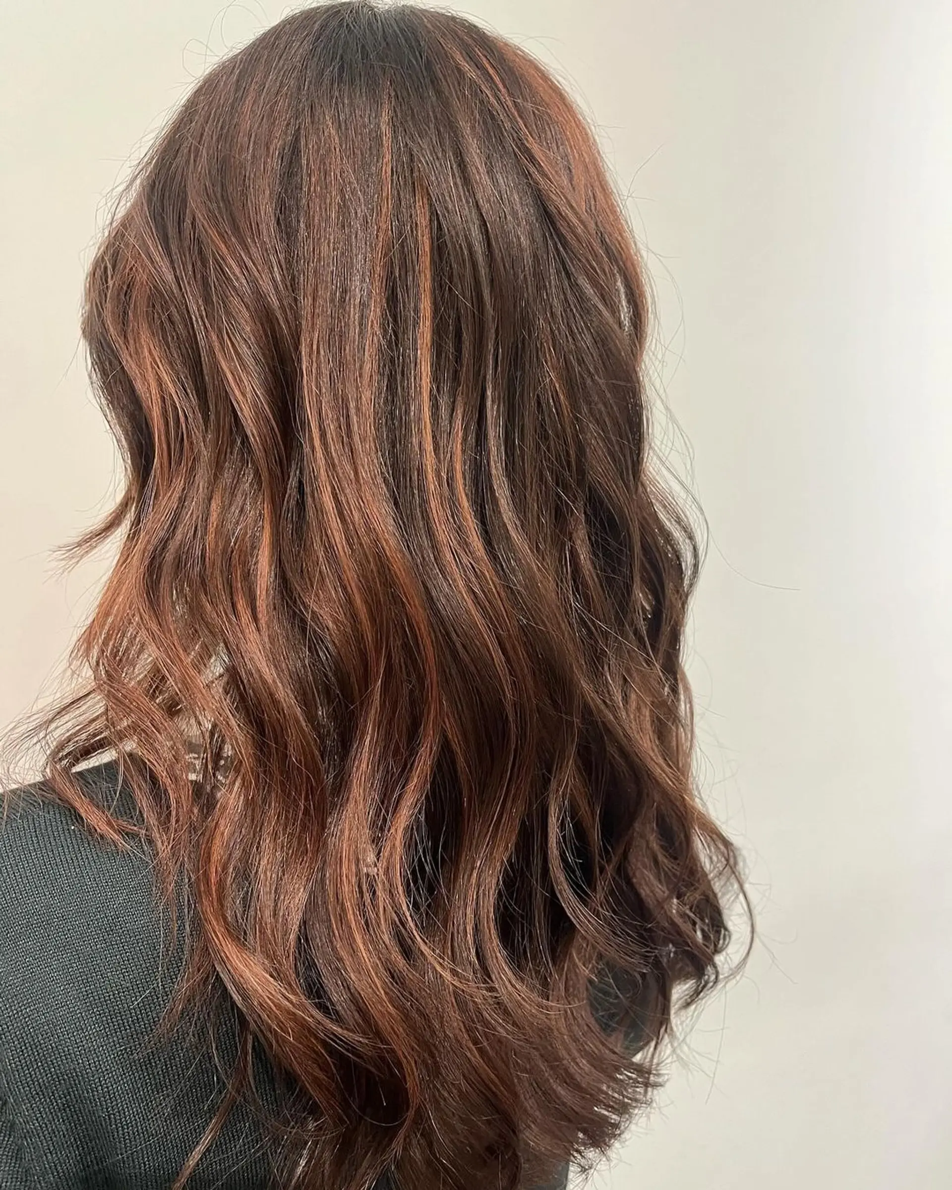 Long, wavy hair with copper and auburn tones, featuring soft waves and a layered cut that adds volume and movement. 1