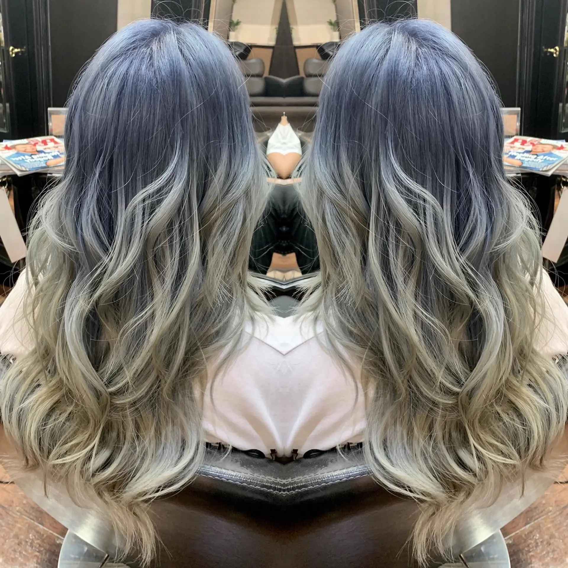 Long wavy hair featuring a seamless color melt transition from smoky denim blue roots into ash blonde and silver ends. 1