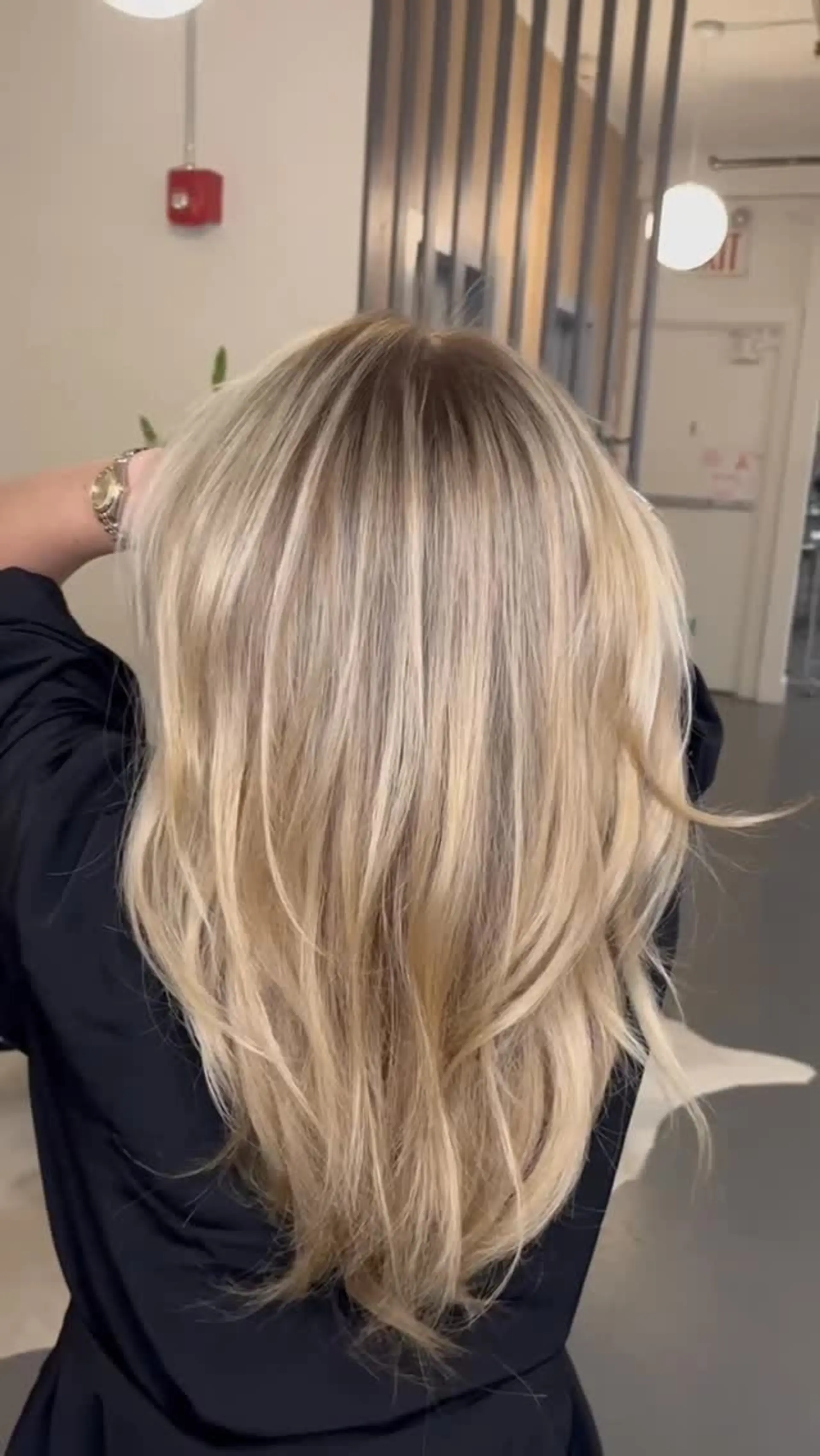 Long multi-tonal blonde hair featuring seamless balayage highlights blending into bright blonde ends with subtle wave texture. 1