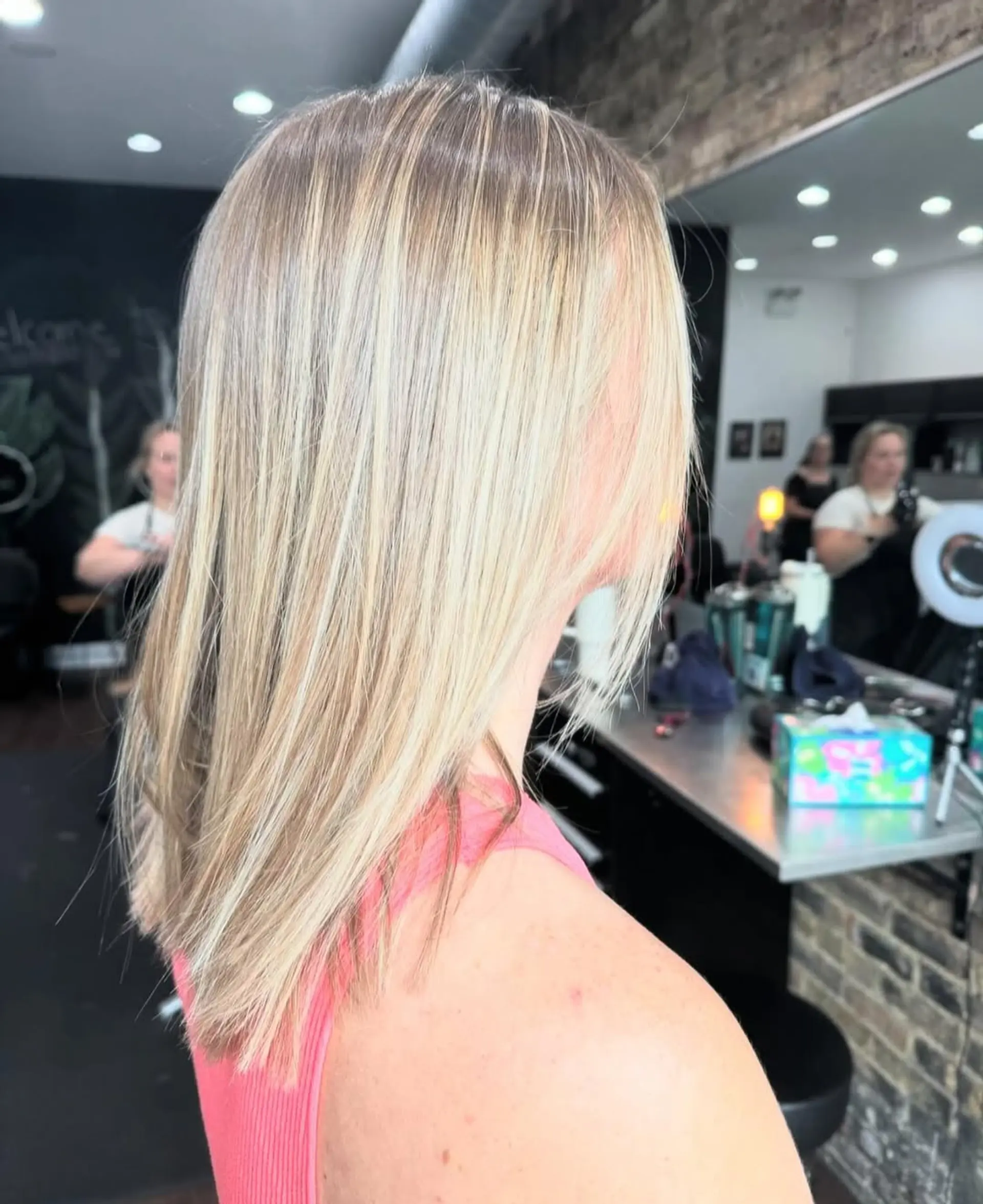 This style features a dimensional blonde balayage, with natural blonde roots seamlessly blended into ash and platinum blonde highlights. The hair is cut into a sleek, medium-length lob, styled straight for a polished finish. 1