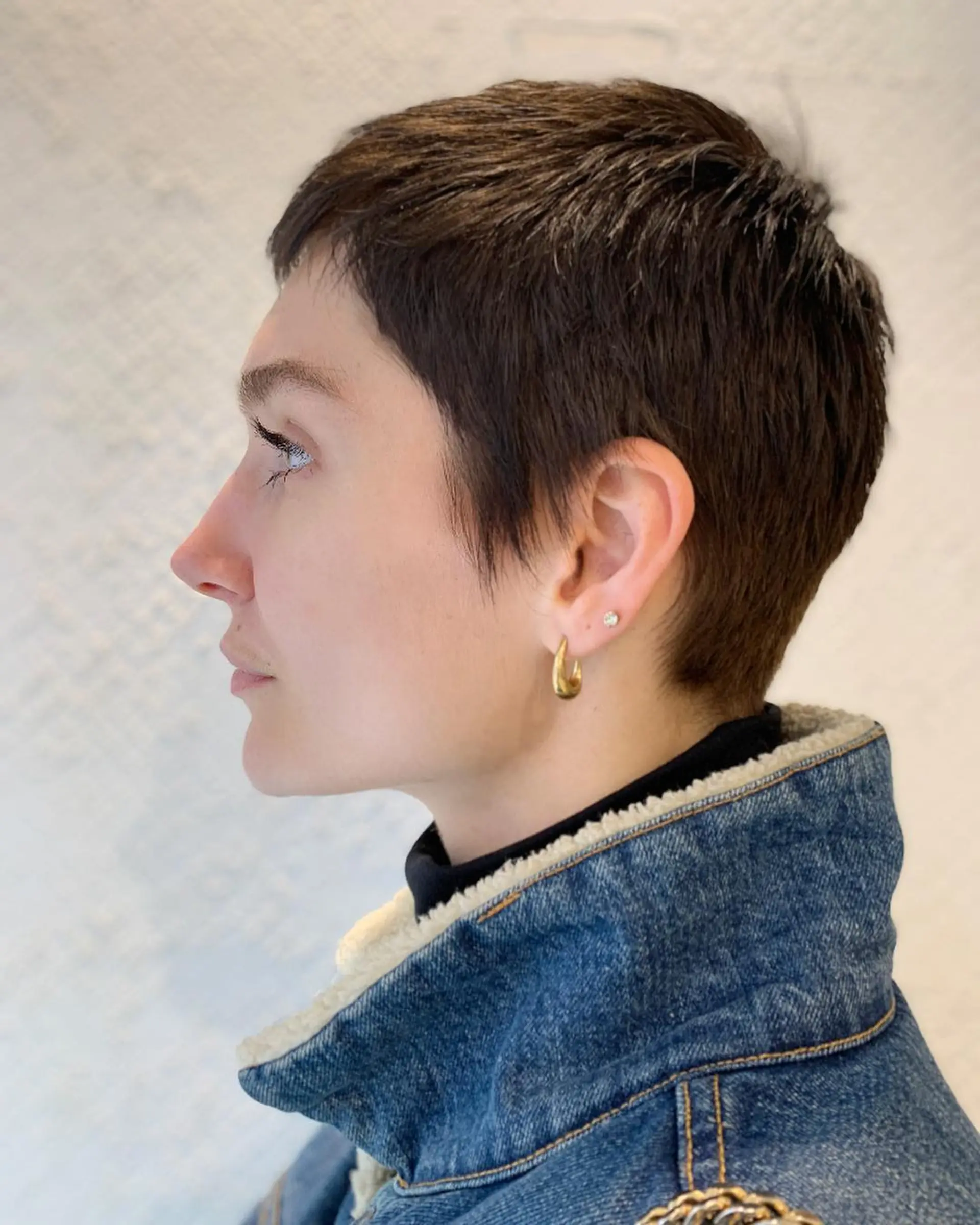 A chic, modern pixie cut with a textured top, tapered nape, and an ear-length fringe, perfect for those seeking a stylish and elegant look. 1