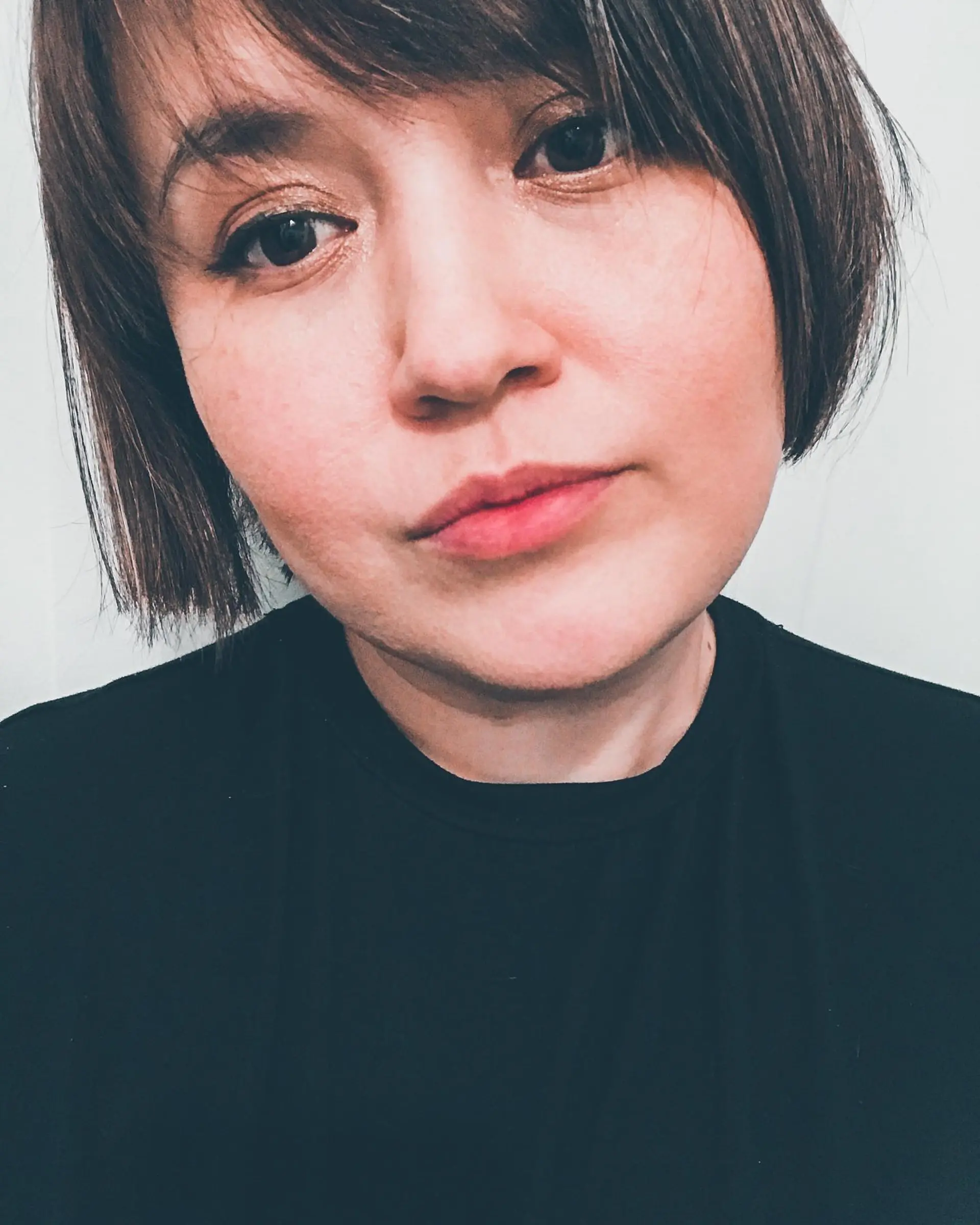 A short dark brown bob cut featuring soft, wispy bangs. 1