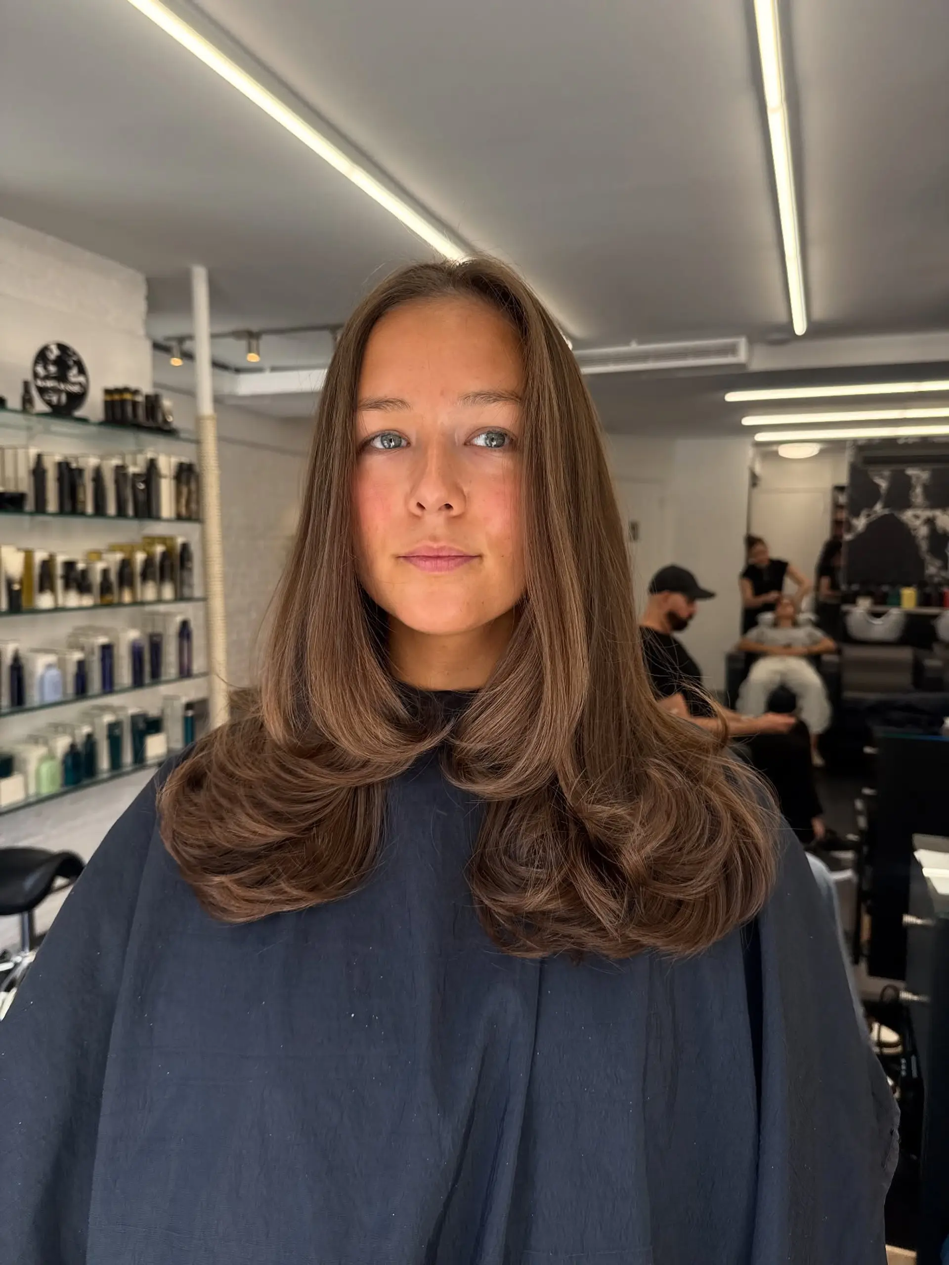 Long chocolate brown hair featuring soft layers styled into a voluminous blowout with flipped-in ends. 1