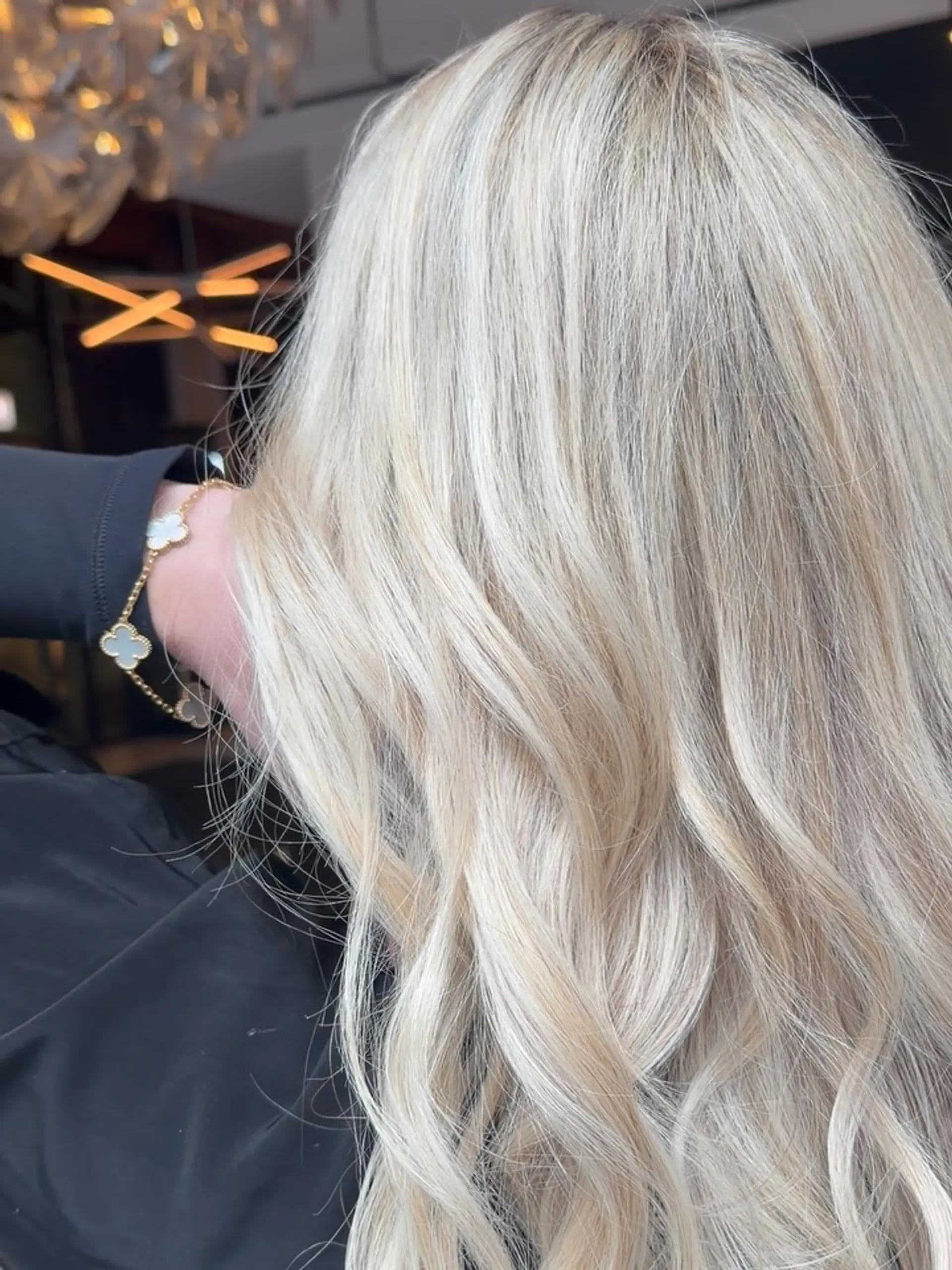 Long, seamless bright blonde hair styled into soft, fluid salon waves. 1