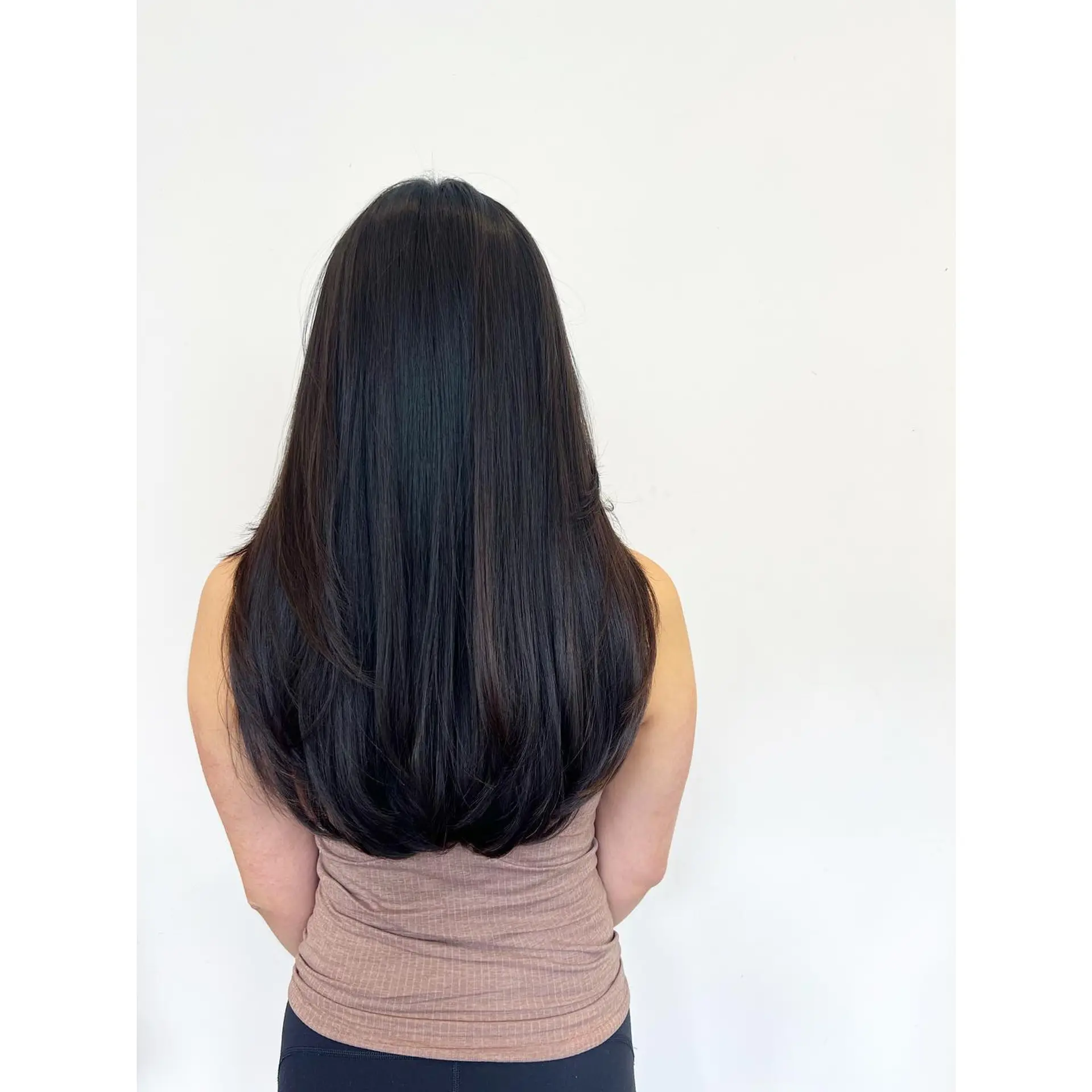 Long, glossy dark hair cut in soft layers with ends smoothly curved inward. 1