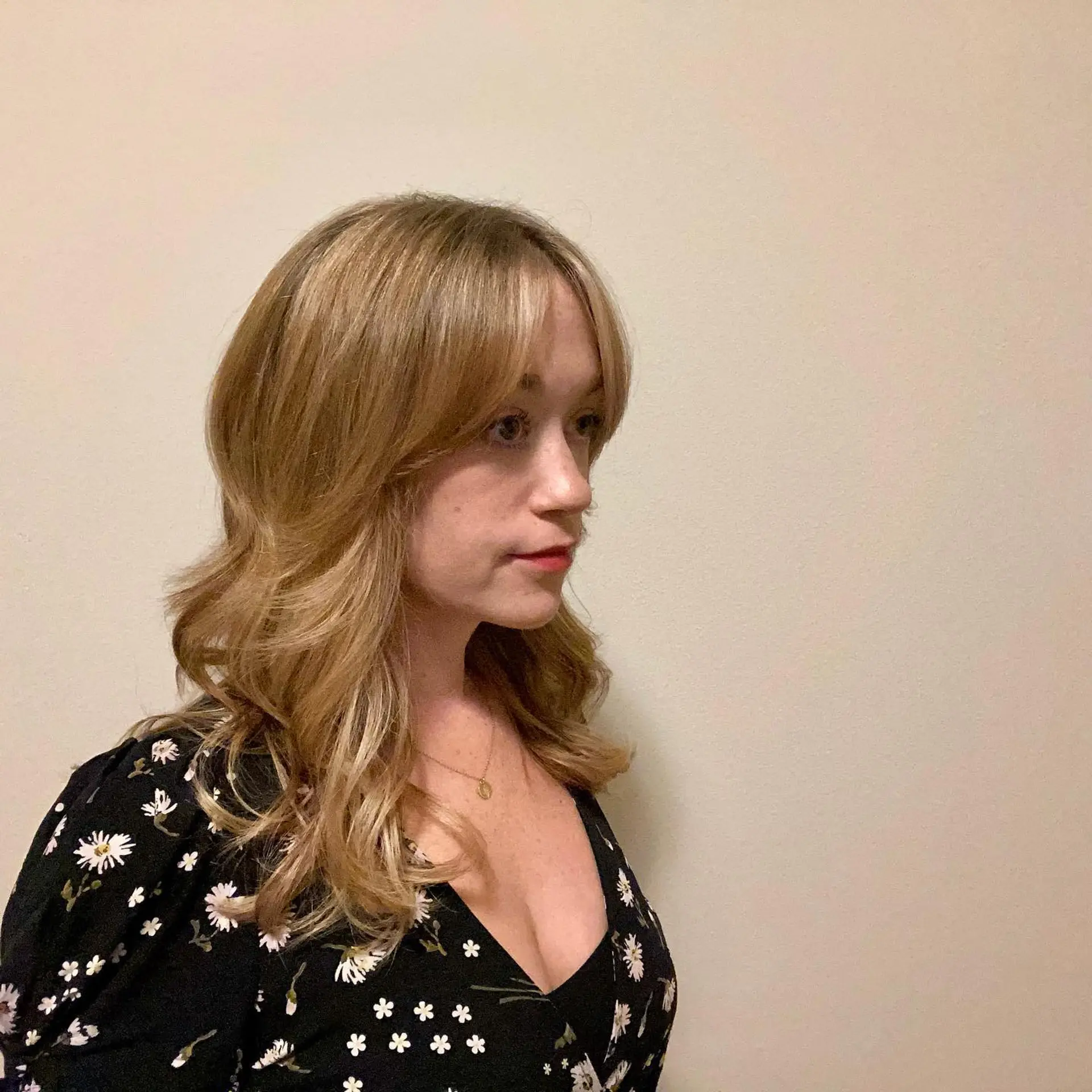 Medium-length warm golden blonde hair styled in soft, loose waves with face-framing curtain bangs. 1