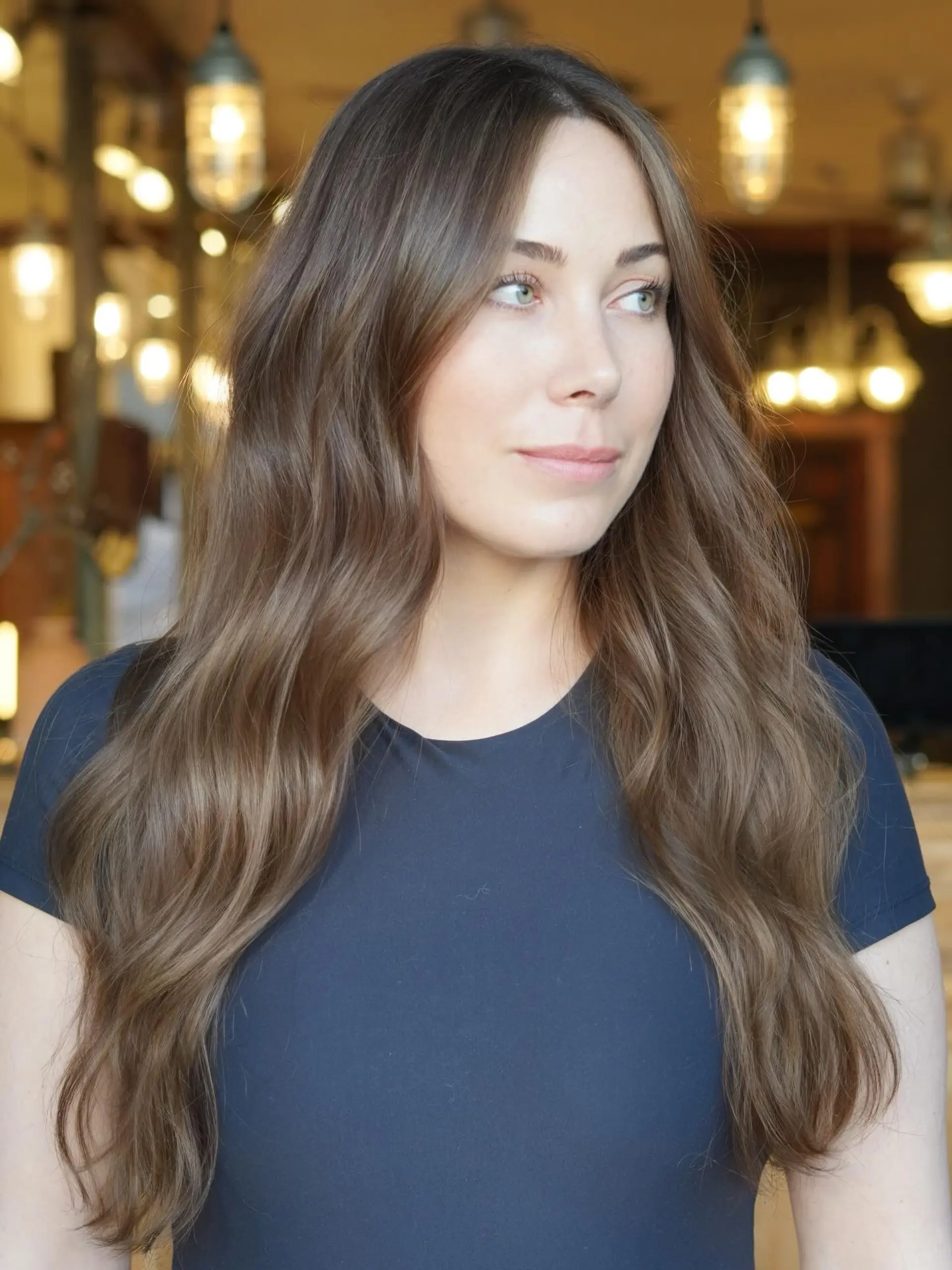 Long, flowing brunette waves accented with delicate sun-kissed highlights for seamless dimension. 1