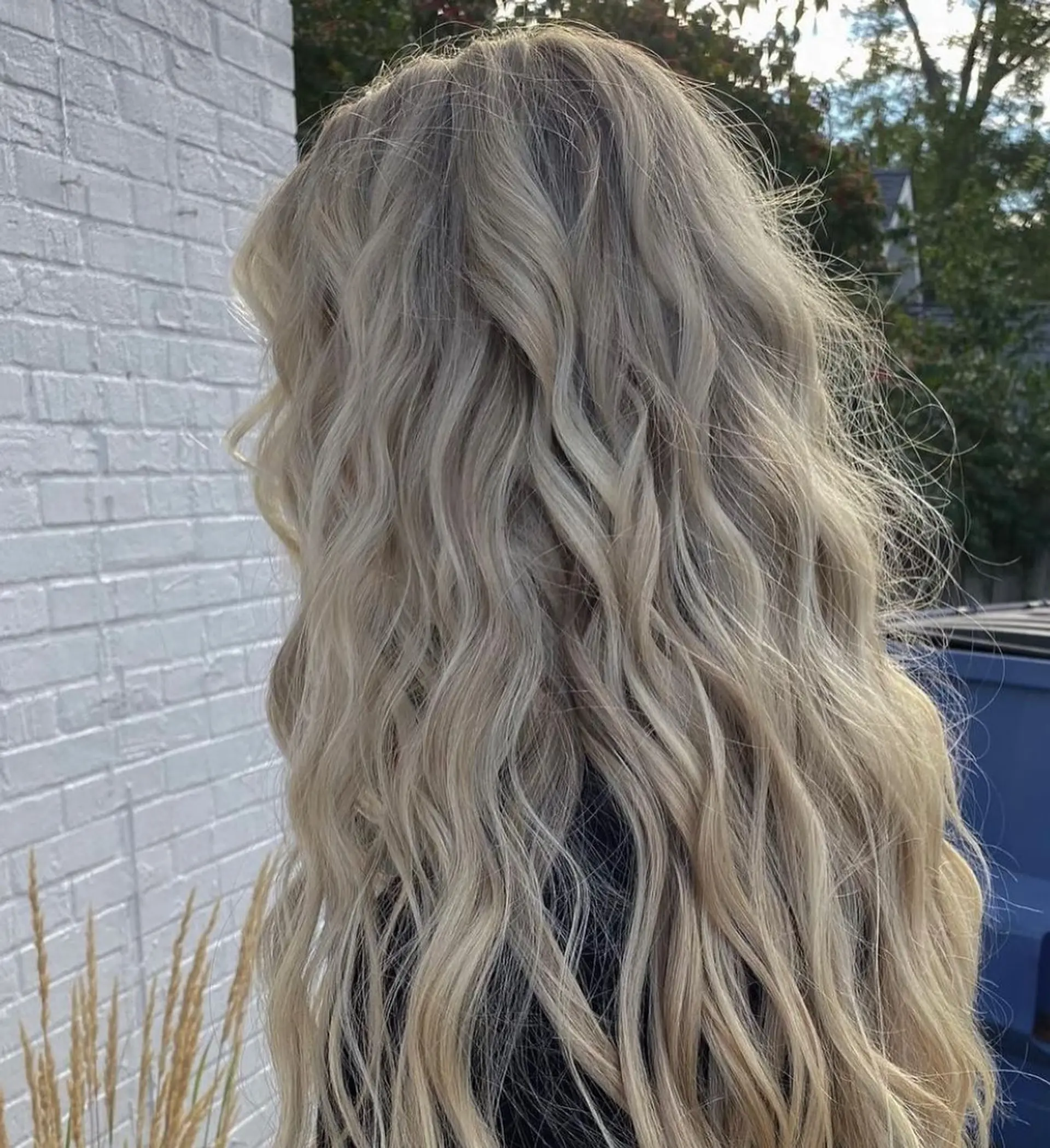 Long, flowing ash blonde hair styled in textured beachy waves with full dimensional highlights. 1
