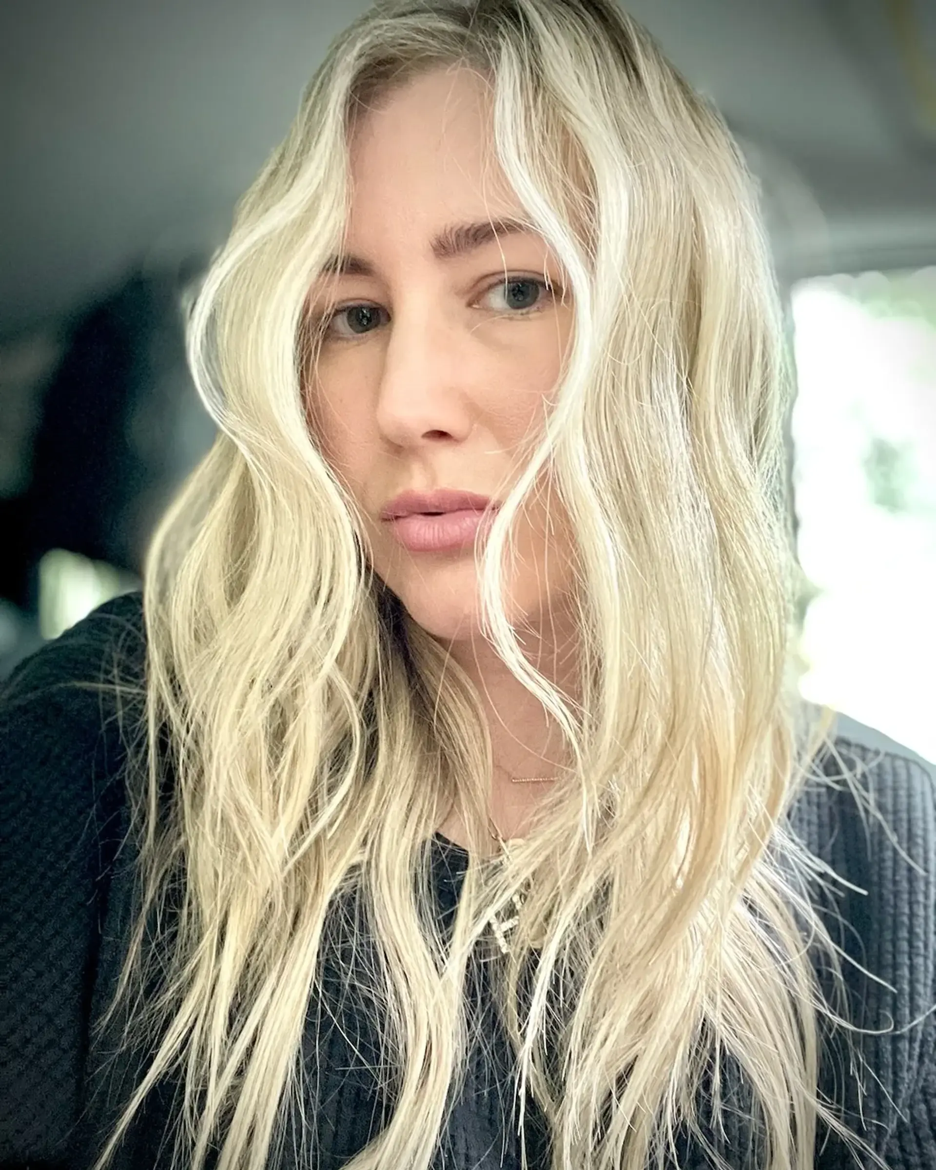 Long bright blonde hair styled with textured, effortless waves falling forward around the face. 1