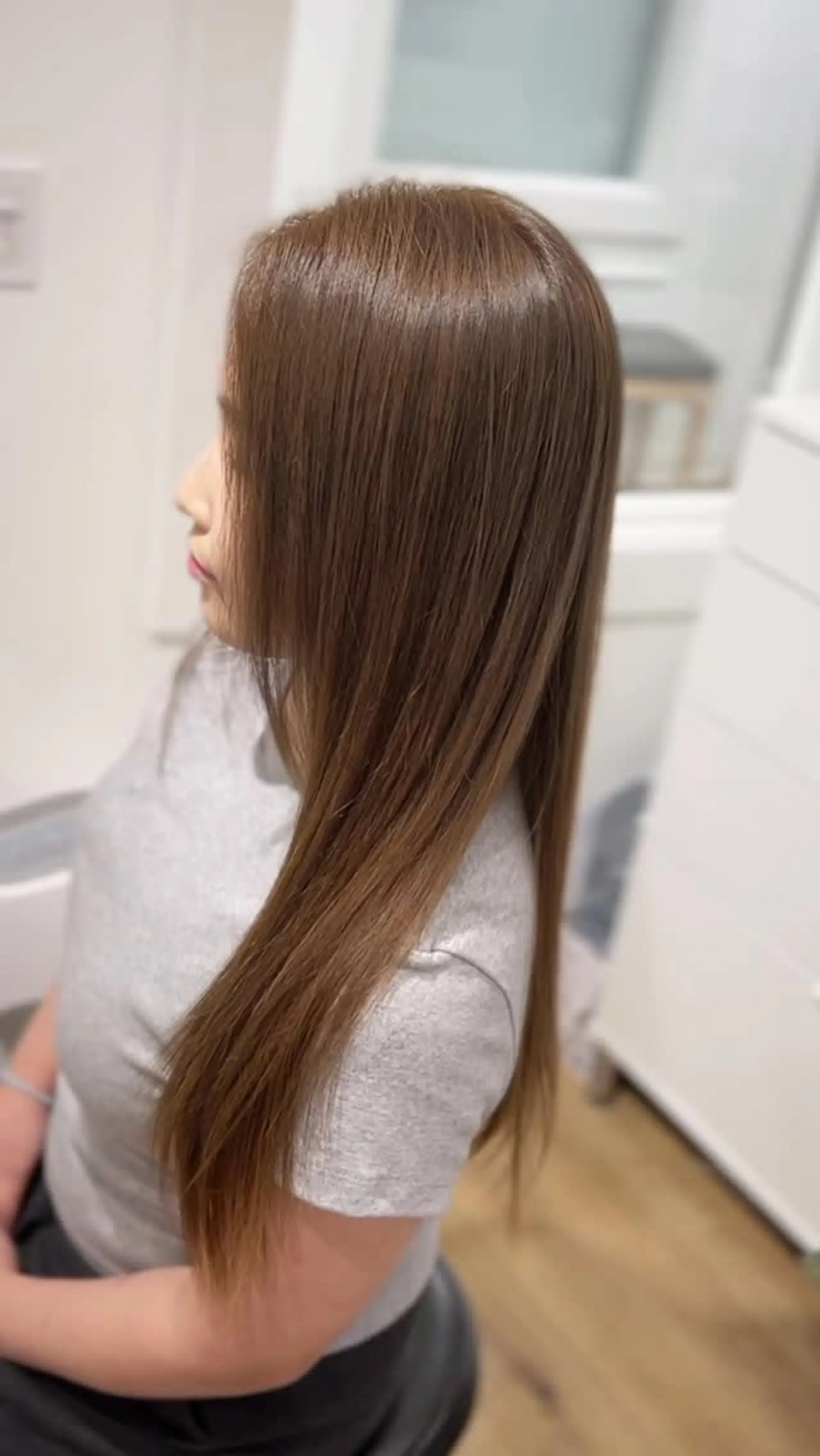 Sleek and straight long hair dyed in a soft, even milky brown tone with a glossy finish. 1