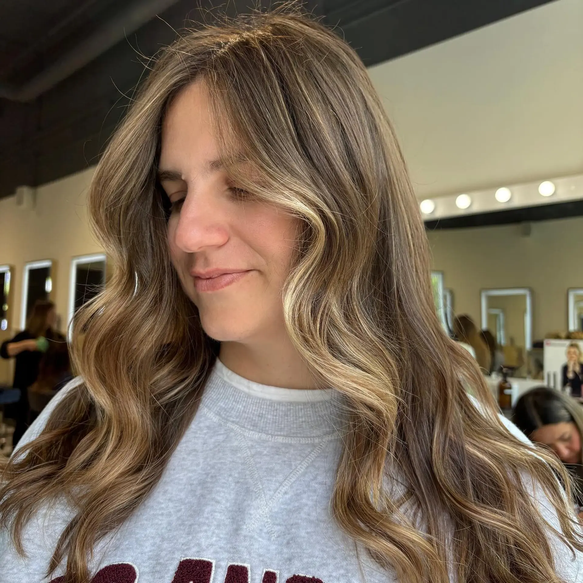Long bronde hair featuring soft, dimensional highlights and a subtle face-framing money piece styled into loose waves. 1