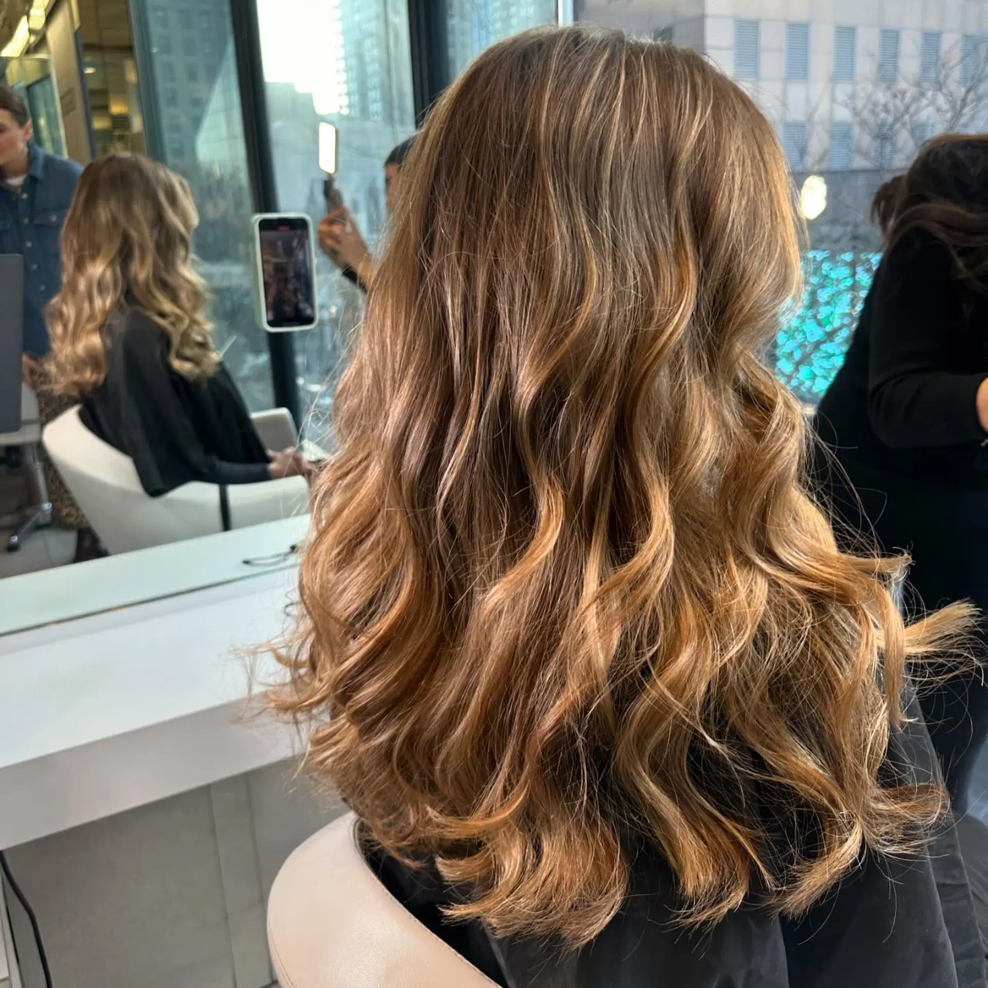 Long dimensional bronde hair styled with soft, cascading waves and seamless sun-kissed highlights. 1