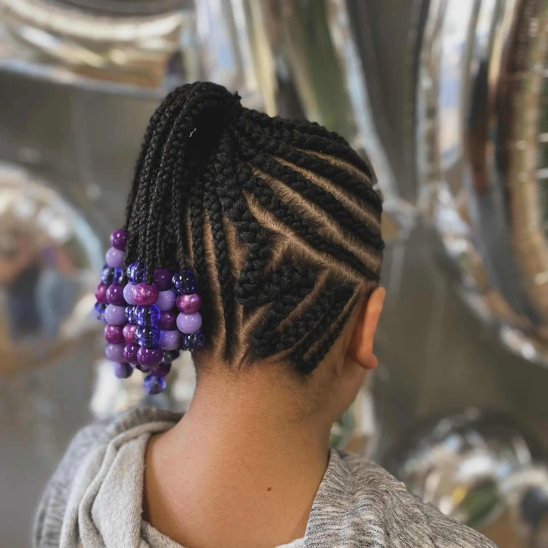 Intricate geometric cornrows gathered into a high braided ponytail finished with purple beads. 1