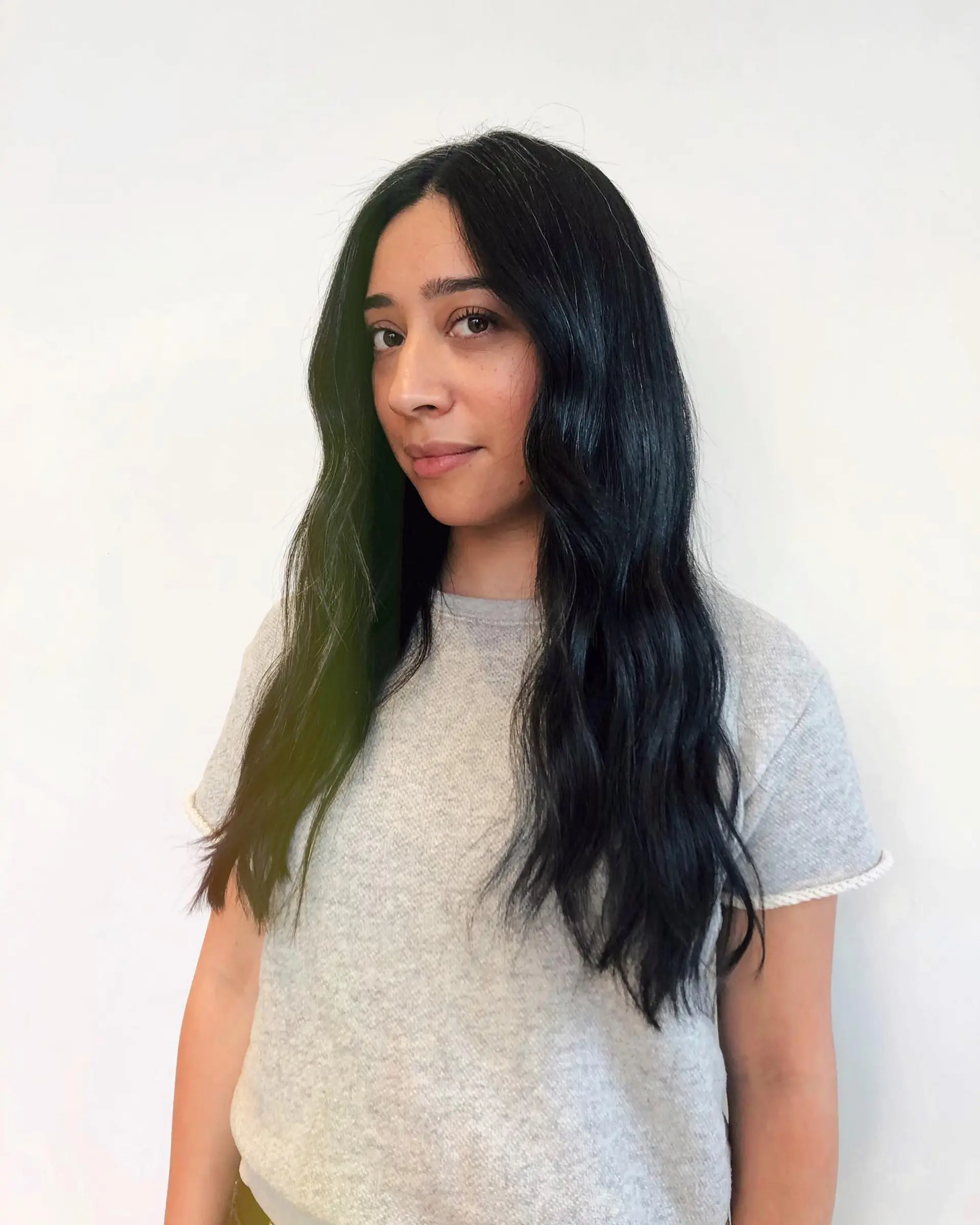 Long jet black hair styled in soft, glossy mermaid waves with a middle part. 1