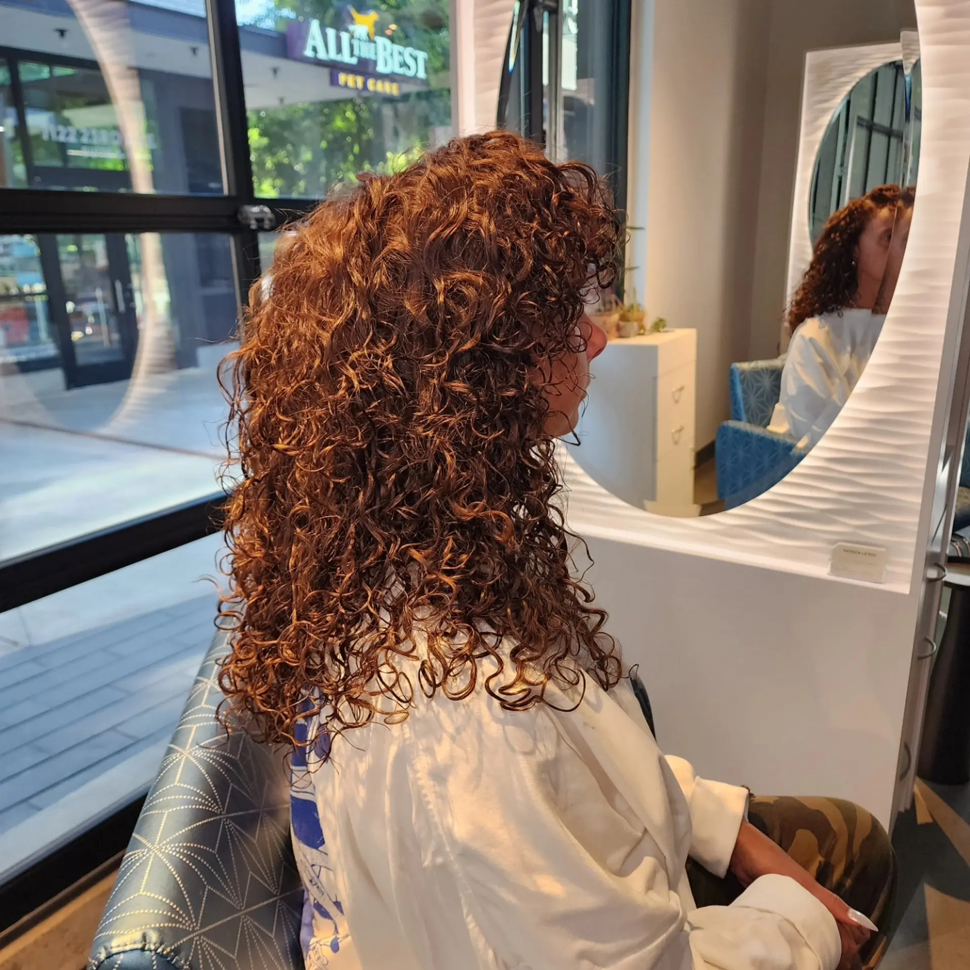 Long, defined auburn curls cut with voluminous layers and full curly bangs. 1