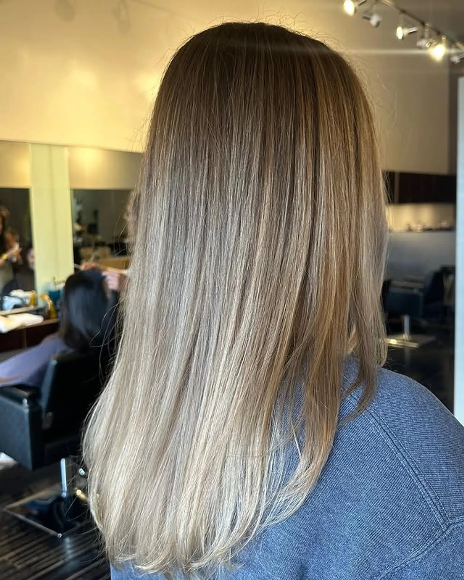 Long, straight hair with a seamless ash blonde balayage for a trendy, low-maintenance look. 1