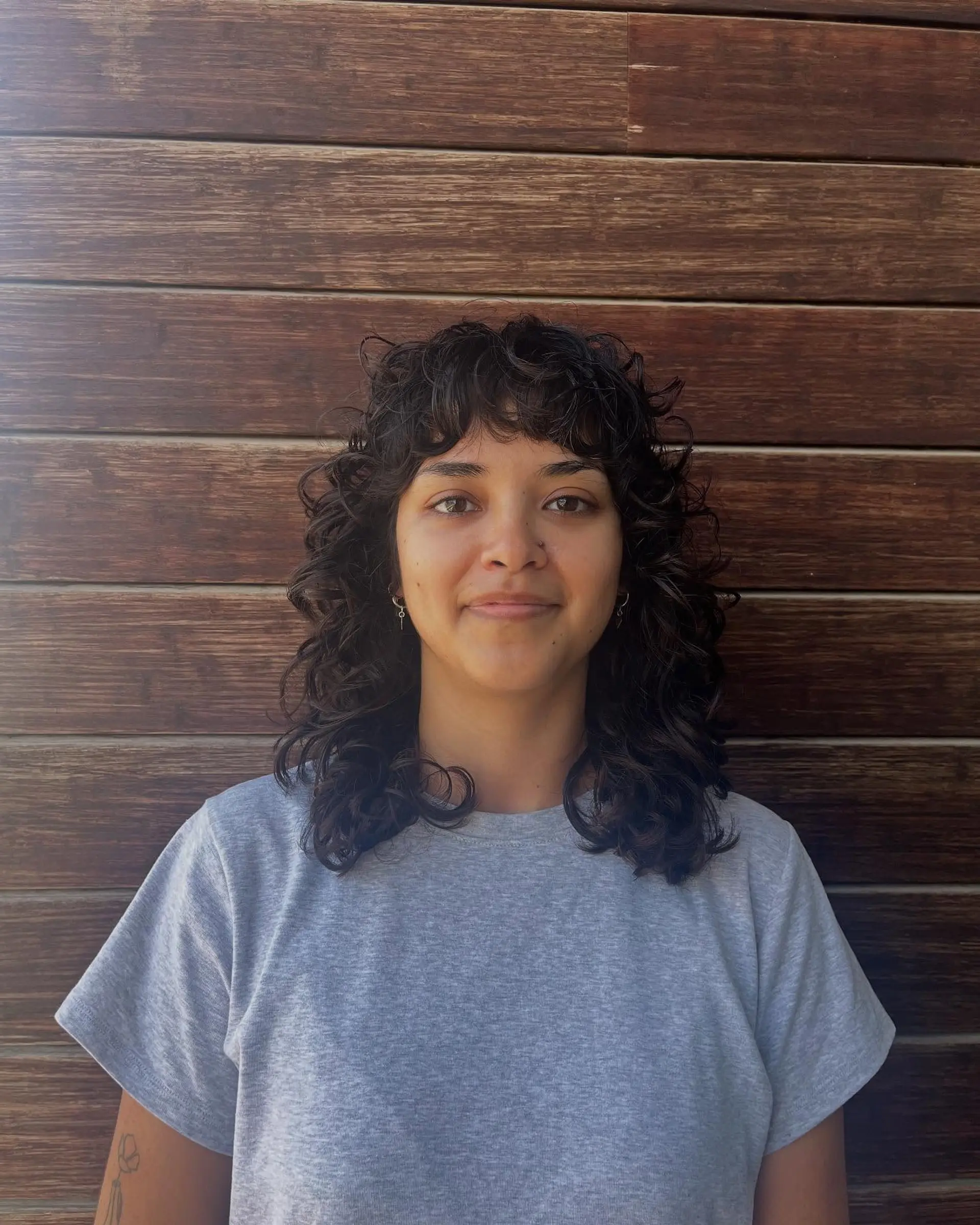 Medium-length dark curly hair cut into a shag style featuring curly fringe/bangs and defined natural ringlets. 1