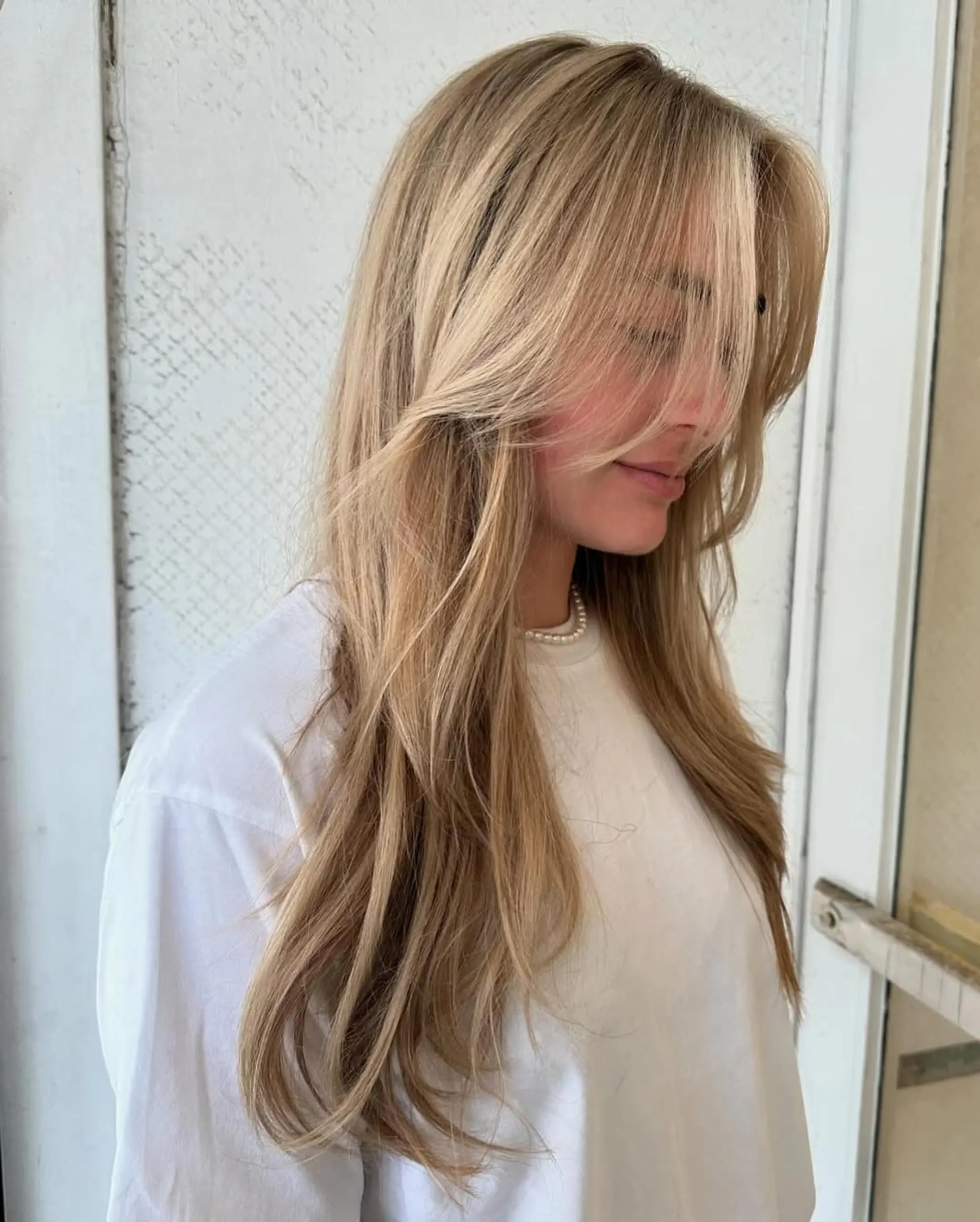 Long, wavy, blonde hair with side-swept bangs and layered waves, featuring natural volume and a beachy texture. 1