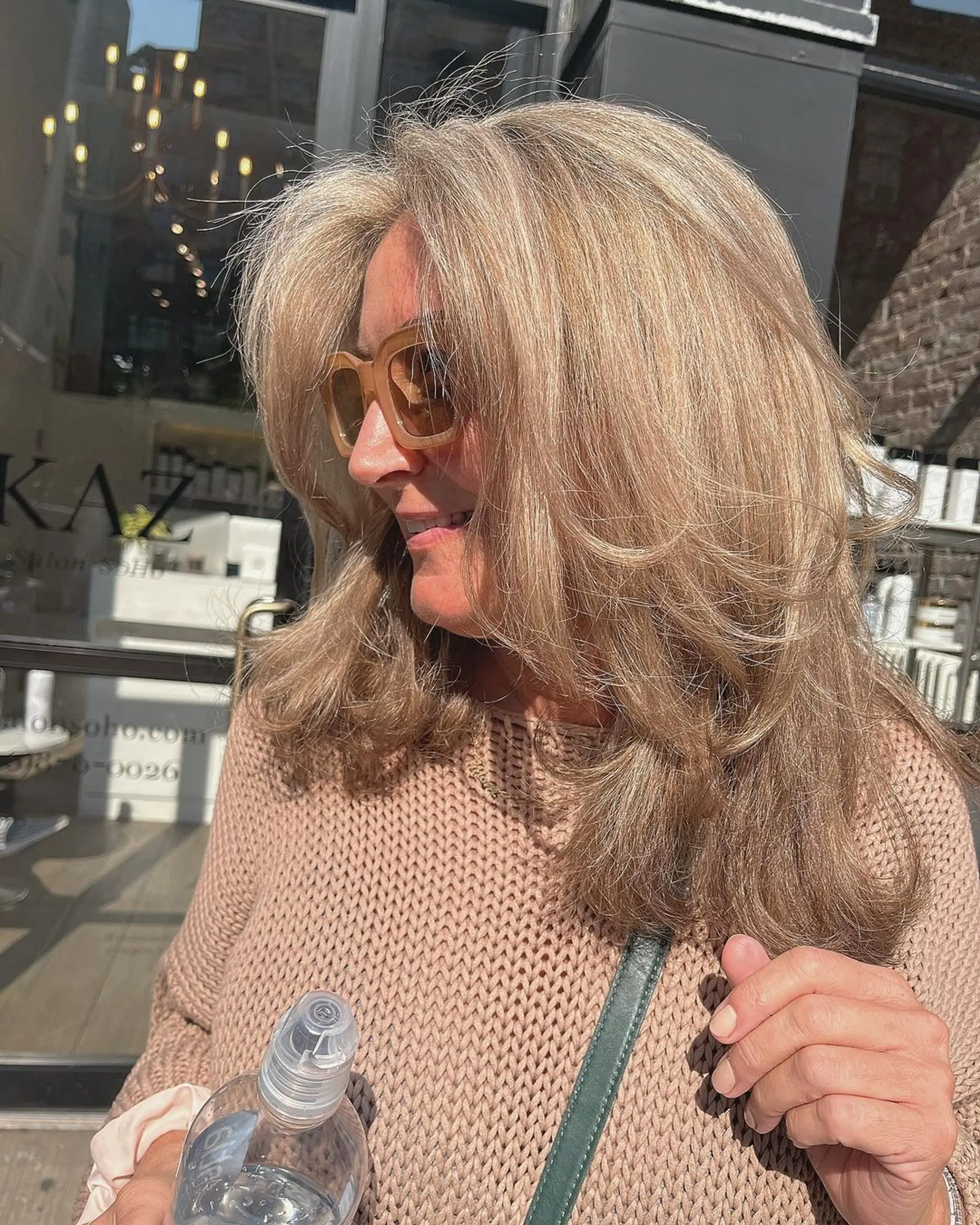 Medium-length, wavy, layered, voluminous waves with honey blonde highlights, side-swept bangs, and textured ends.