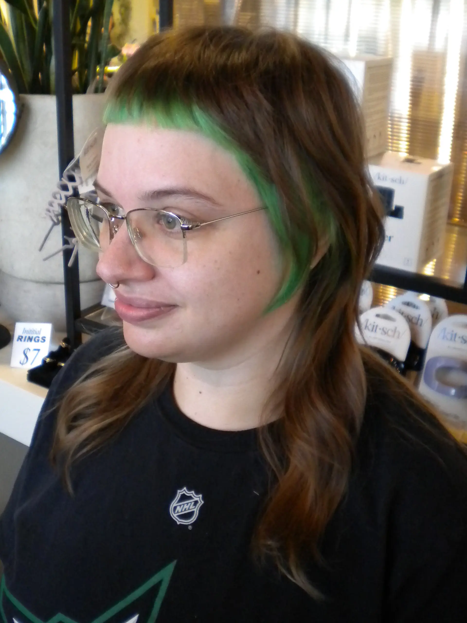 A modern shag mullet haircut featuring vibrant green micro bangs and matching face-framing color blocking on medium-length brown hair. 1