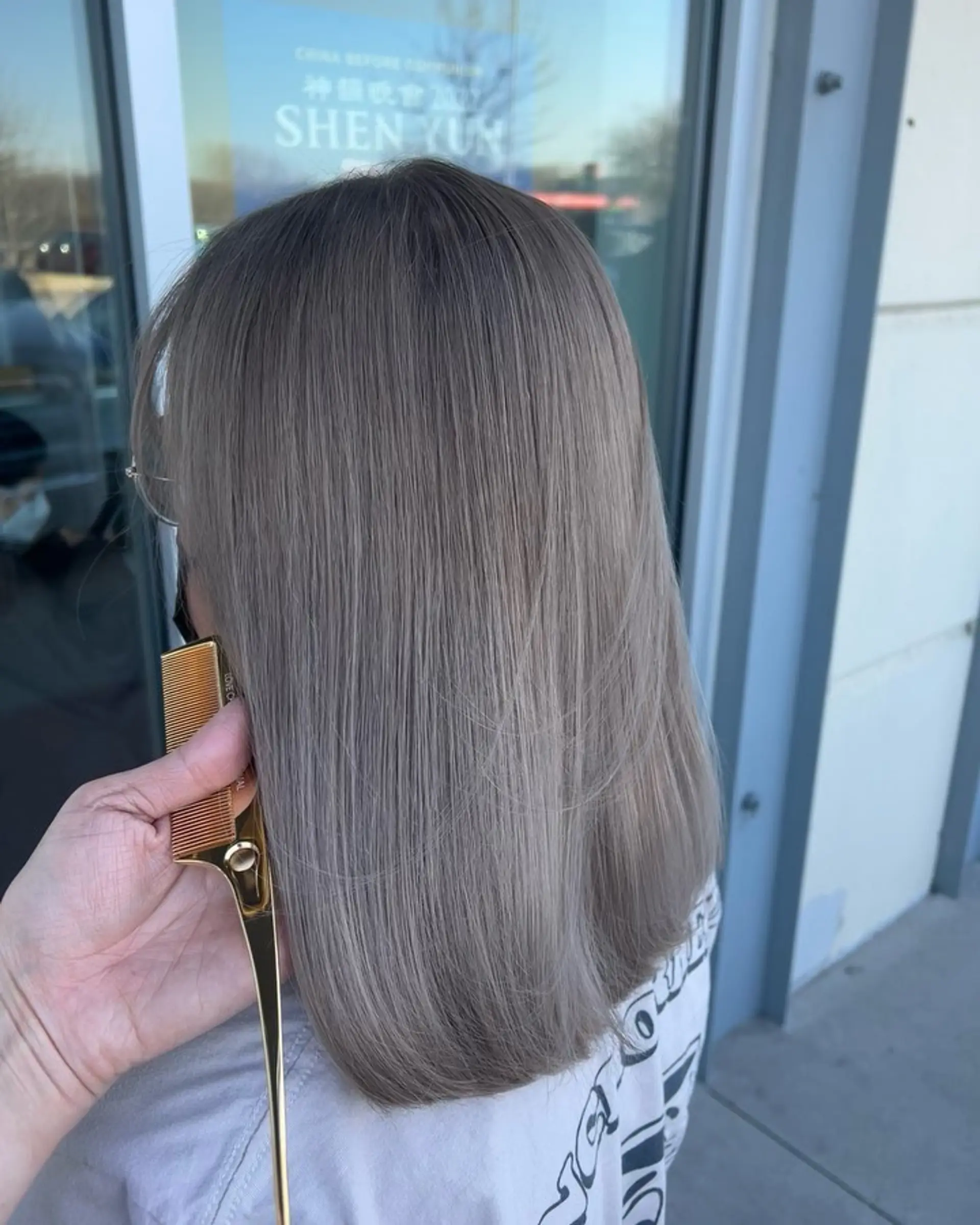 A sleek, medium-length lob colored in a seamless cool ash beige shade. 1