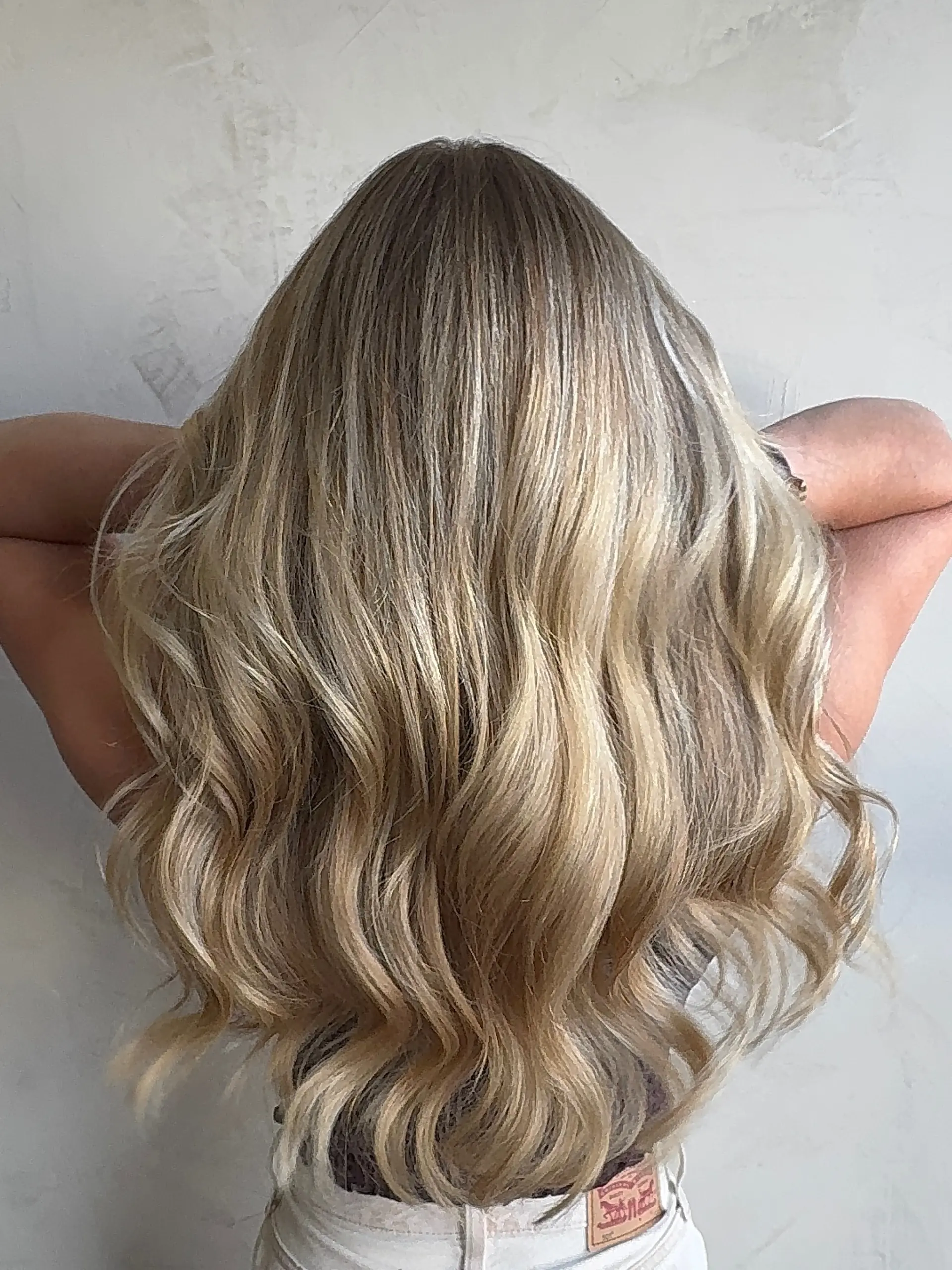 Long blonde hair featuring seamless dimensional highlights styled in loose, voluminous waves. 1