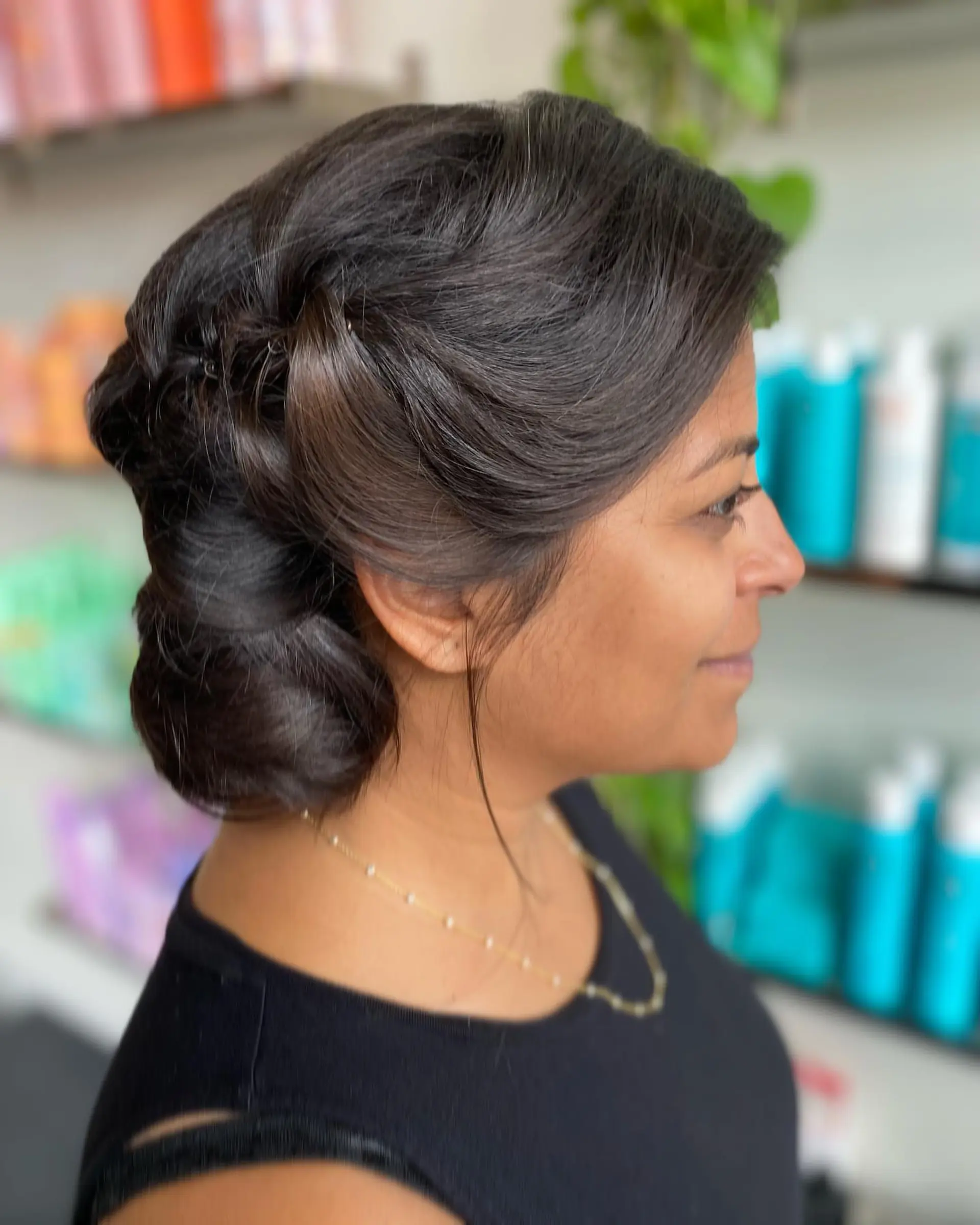 An elegant bridal low chignon featuring sleek swept-back sections gathered gracefully at the nape. 1