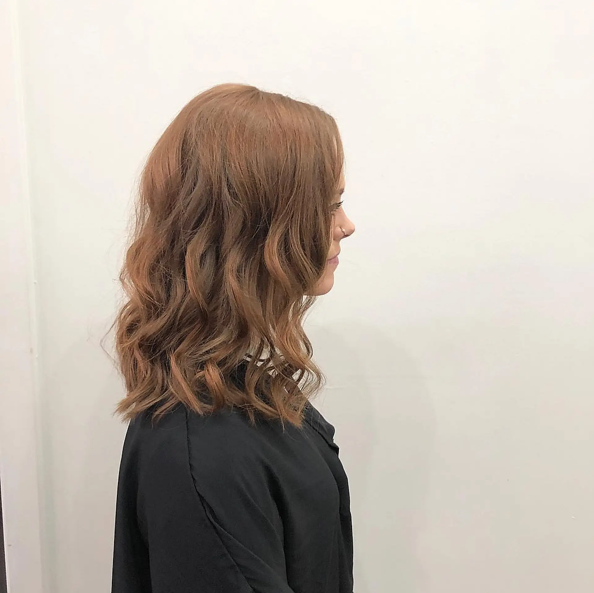 A shoulder-length wavy lob cut styled in soft, loose waves with warm auburn-brown tones. 1