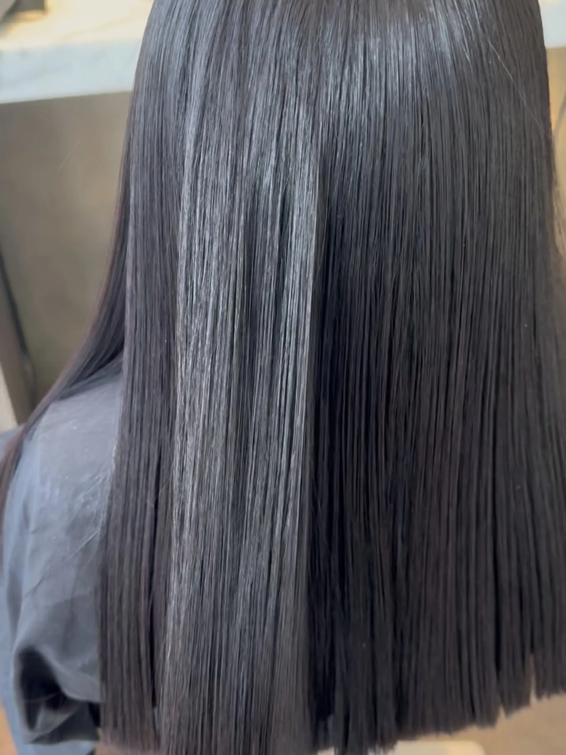 Ultra-smooth, glossy straight dark hair styled to a high-shine finish. 1