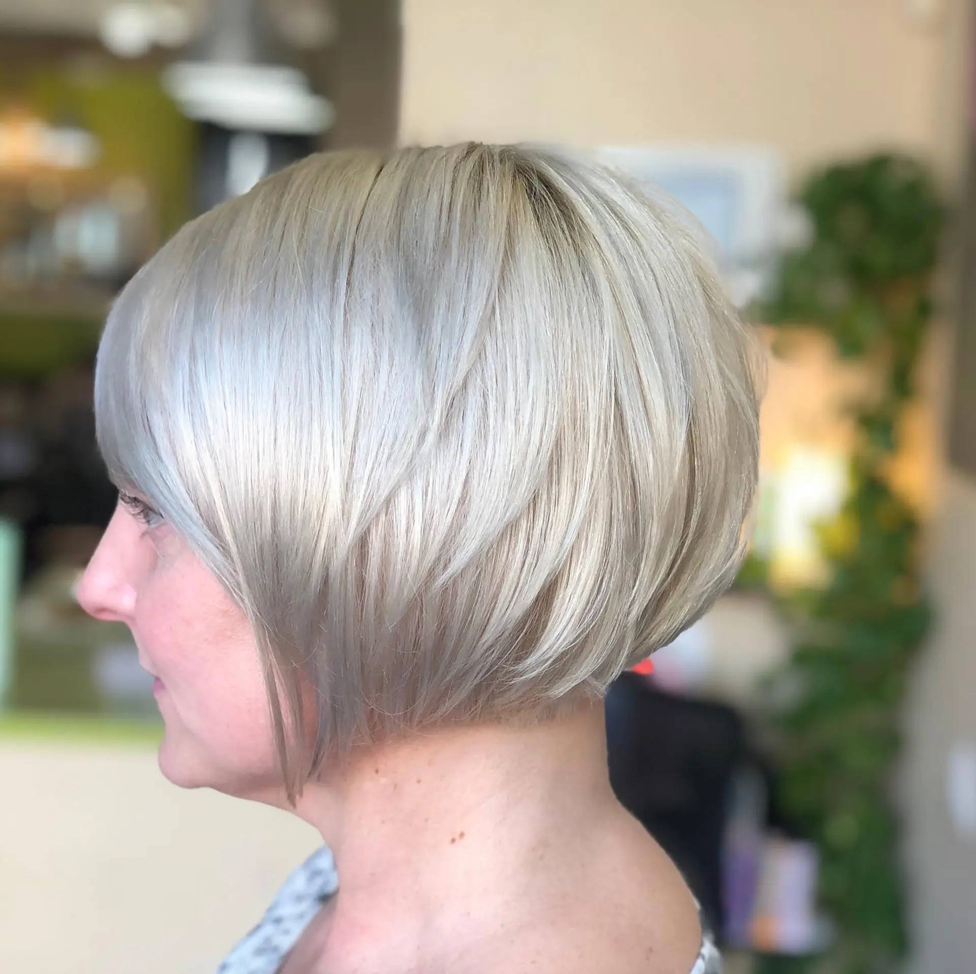 A sleek, stacked bob haircut cut above the jawline with subtle graduation and a cool platinum blonde tone. 1