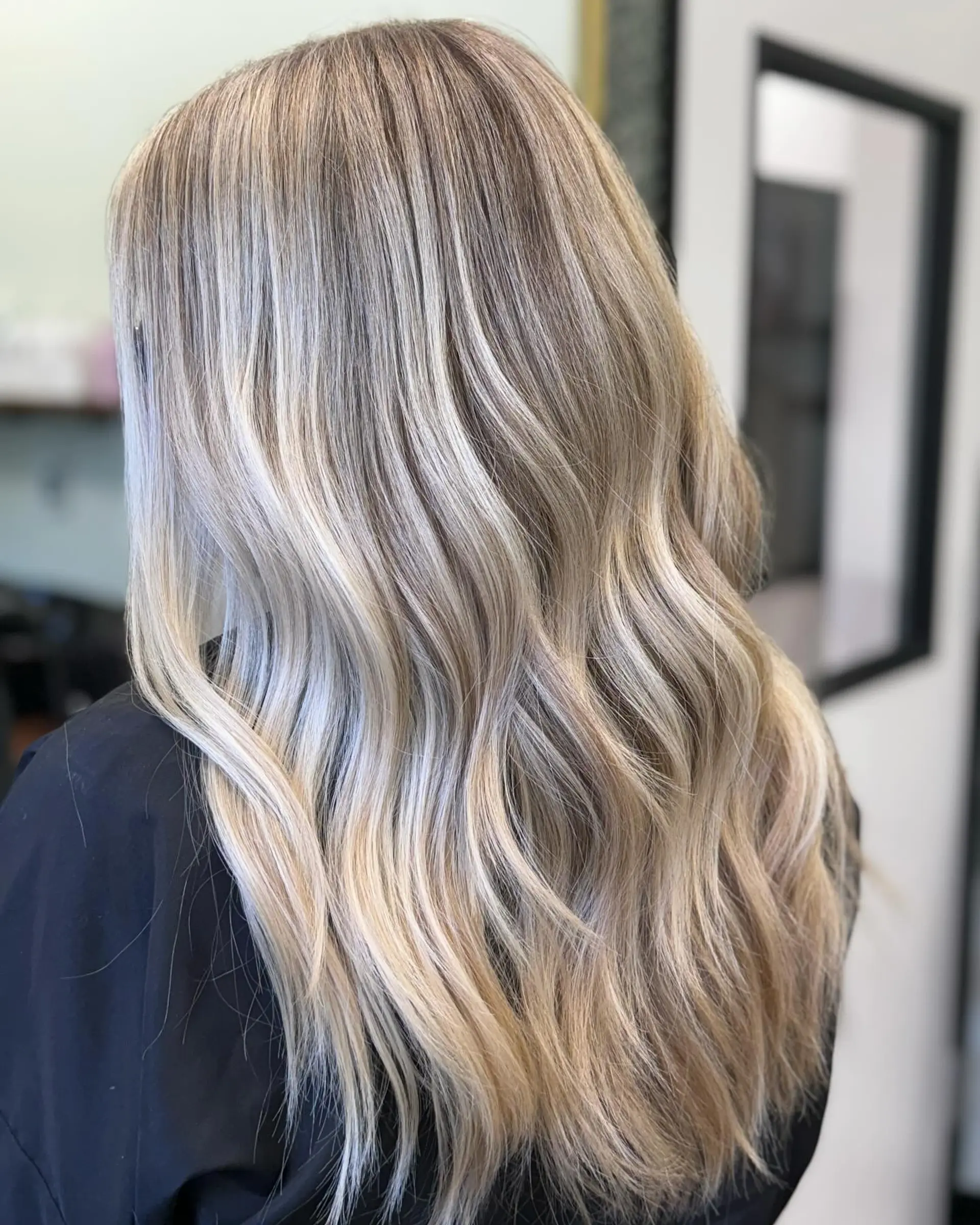 Long hair with an icy blonde balayage styled in soft, loose waves. 1
