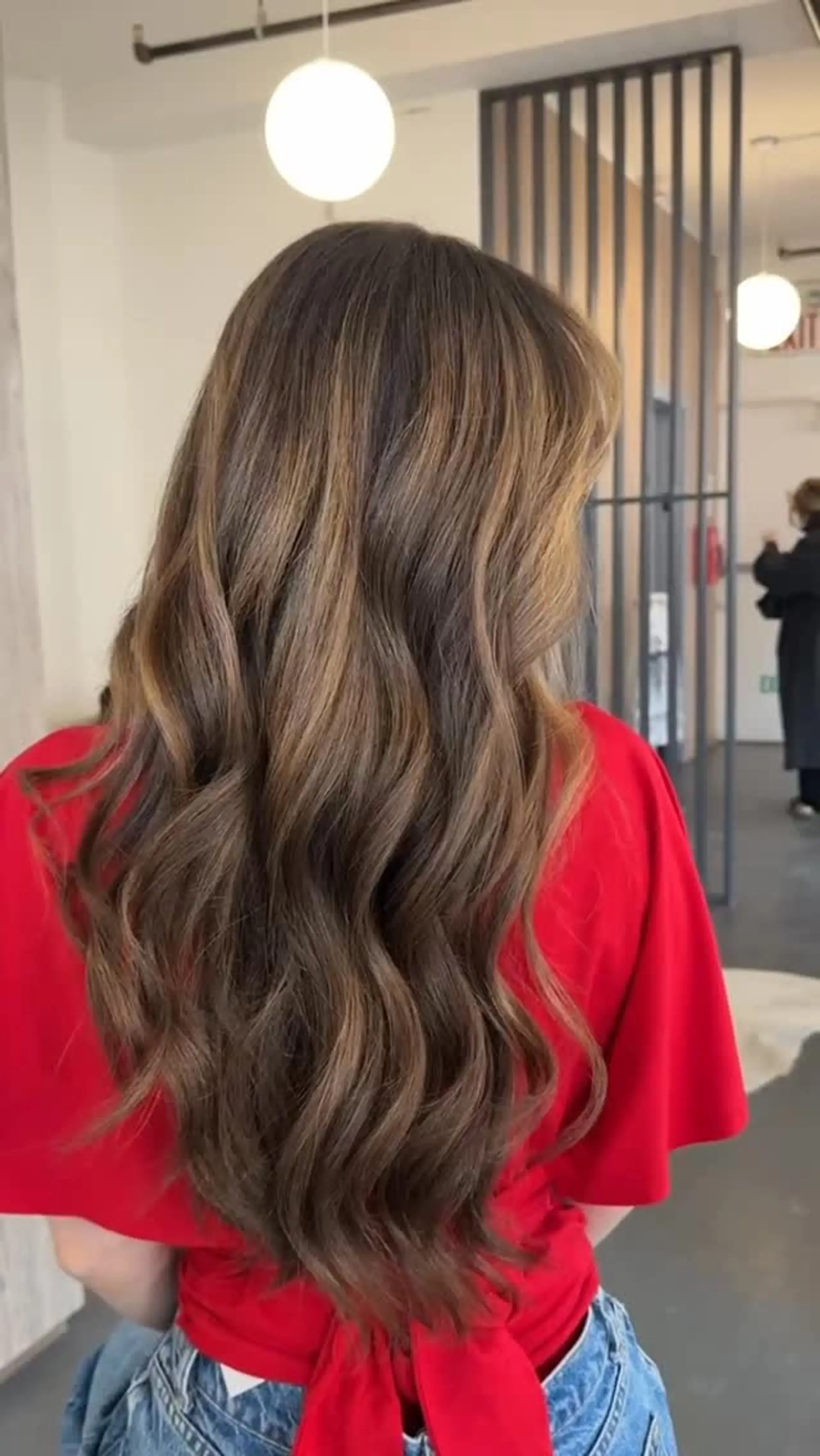 Long flowing hair styled in loose waves featuring a rich brunette base highlighted with warm caramel and golden balayage tones. 1