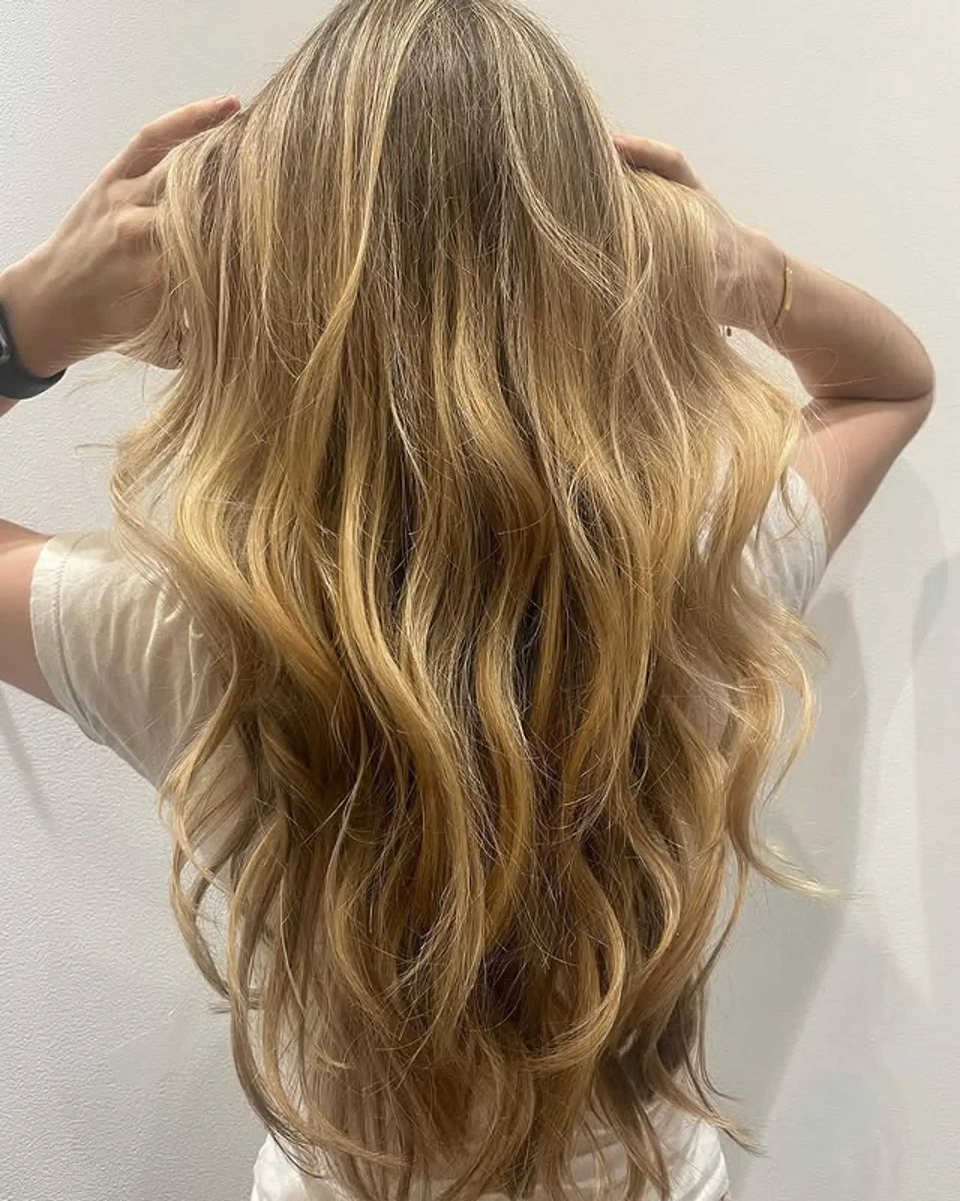 A long, wavy hairstyle with a balayage that blends blonde highlights throughout. 1