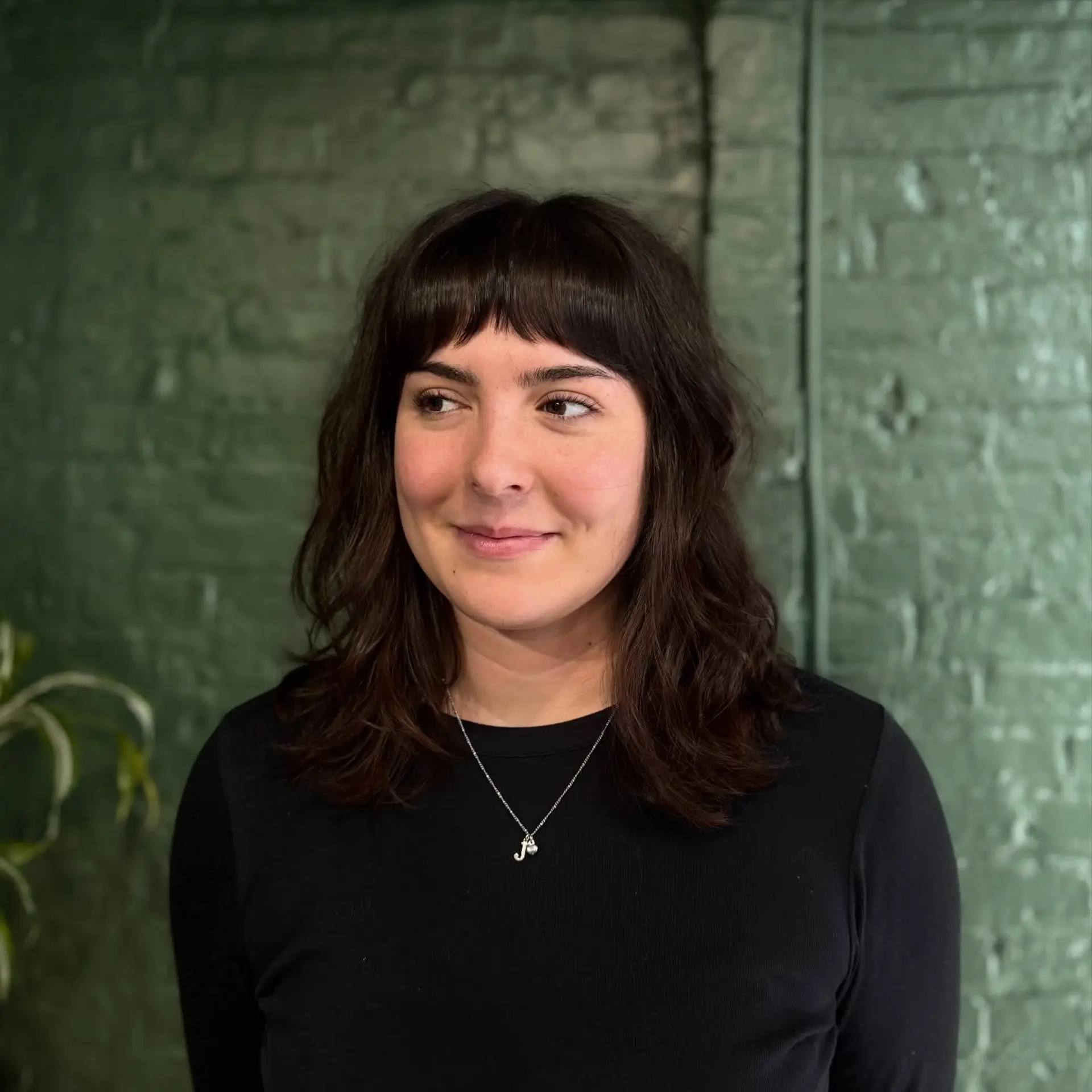 Medium-length dark brunette cut featuring soft, natural wavy texture and short, slightly textured blunt baby bangs. 1