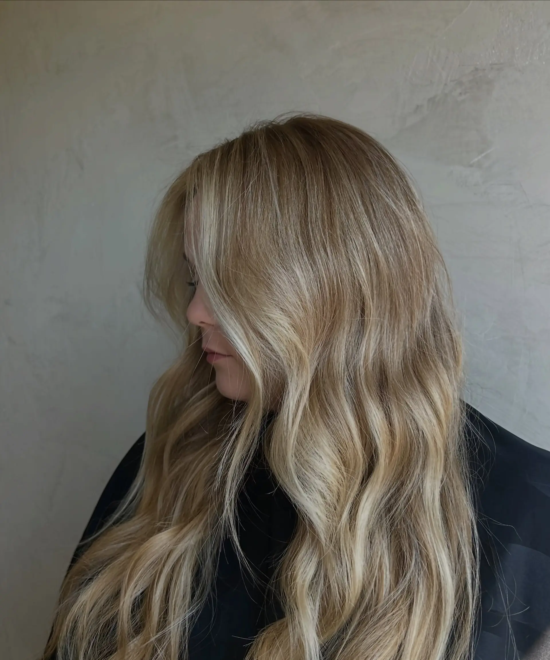 Long dimensional blonde hair styled in soft, cascading waves with brighter face-framing pieces. 1