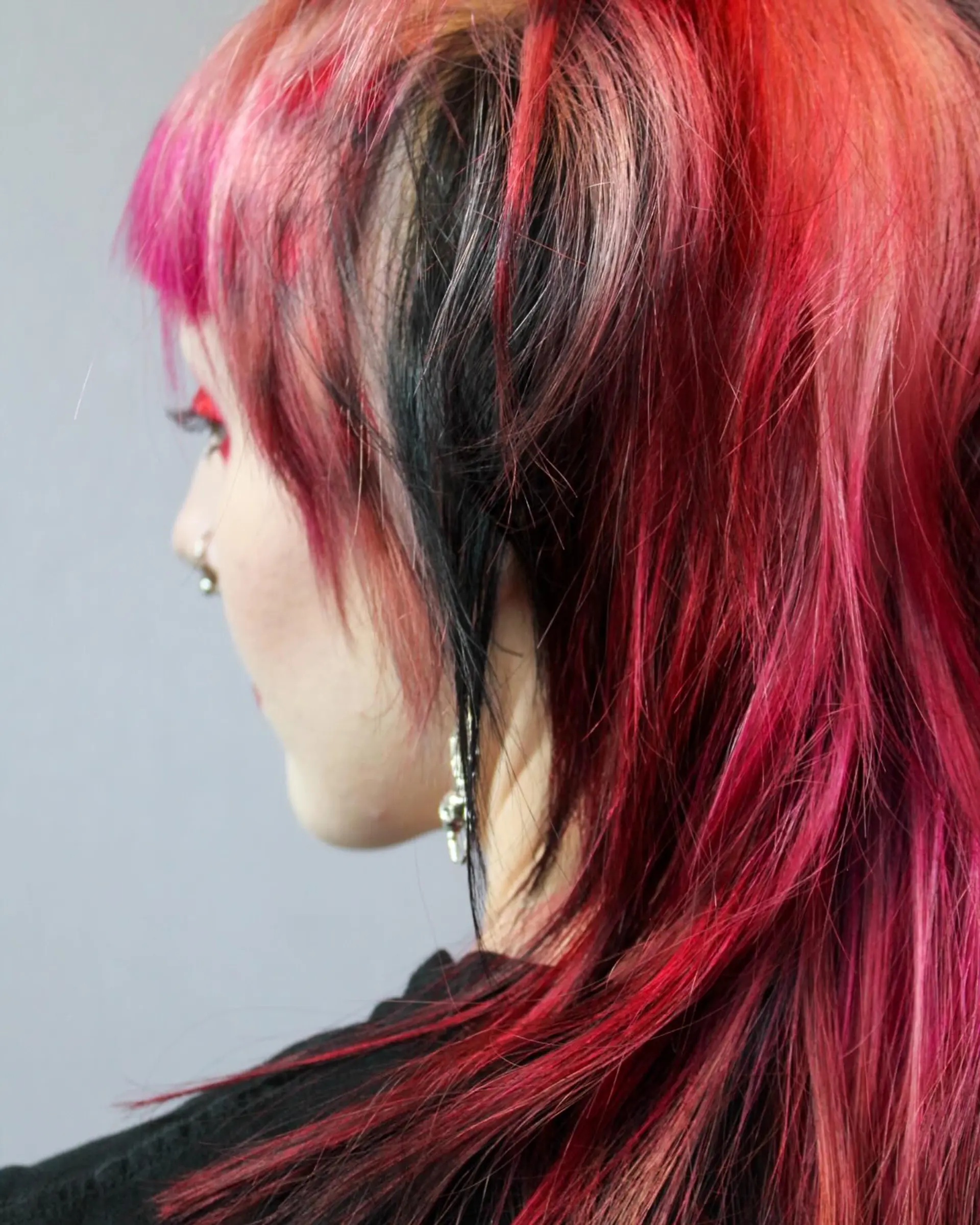 A wolf cut with choppy layers and vibrant red, pink, and black colors. 1