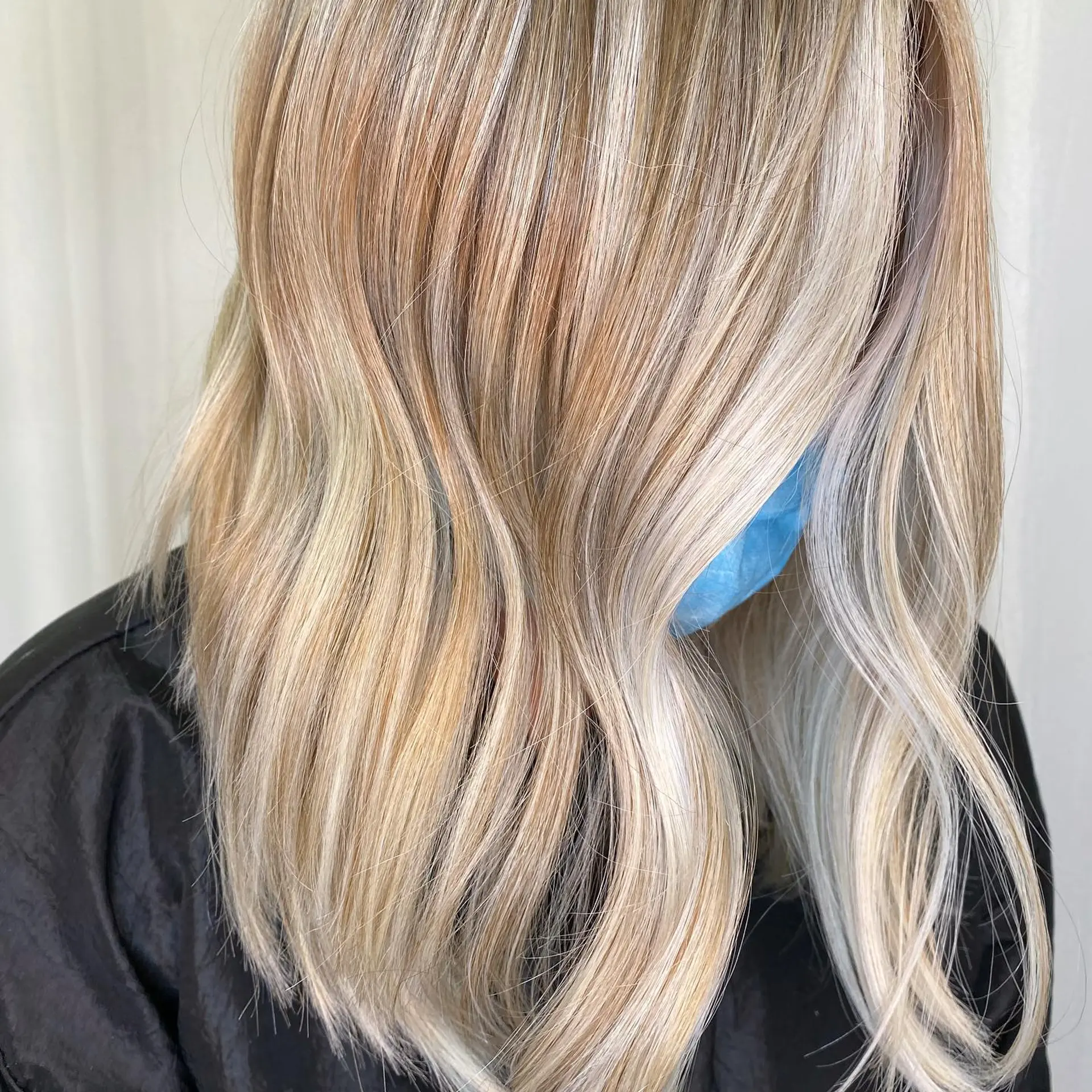 A beautiful medium-length lob styled with soft, effortless waves. The color is a sophisticated blend of dimensional blonde, featuring both warm golden and cool ash tones that create depth and movement. 1