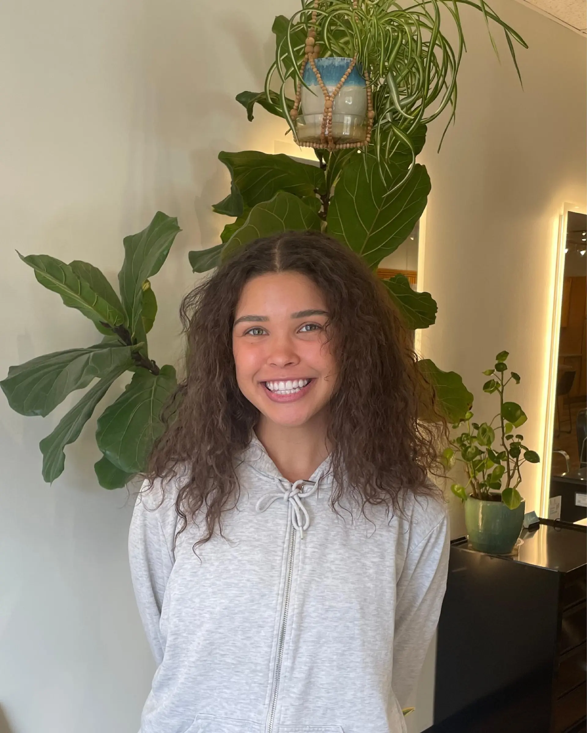 Medium-length layered curly hairstyle parted down the center with natural texture and soft volume. 1