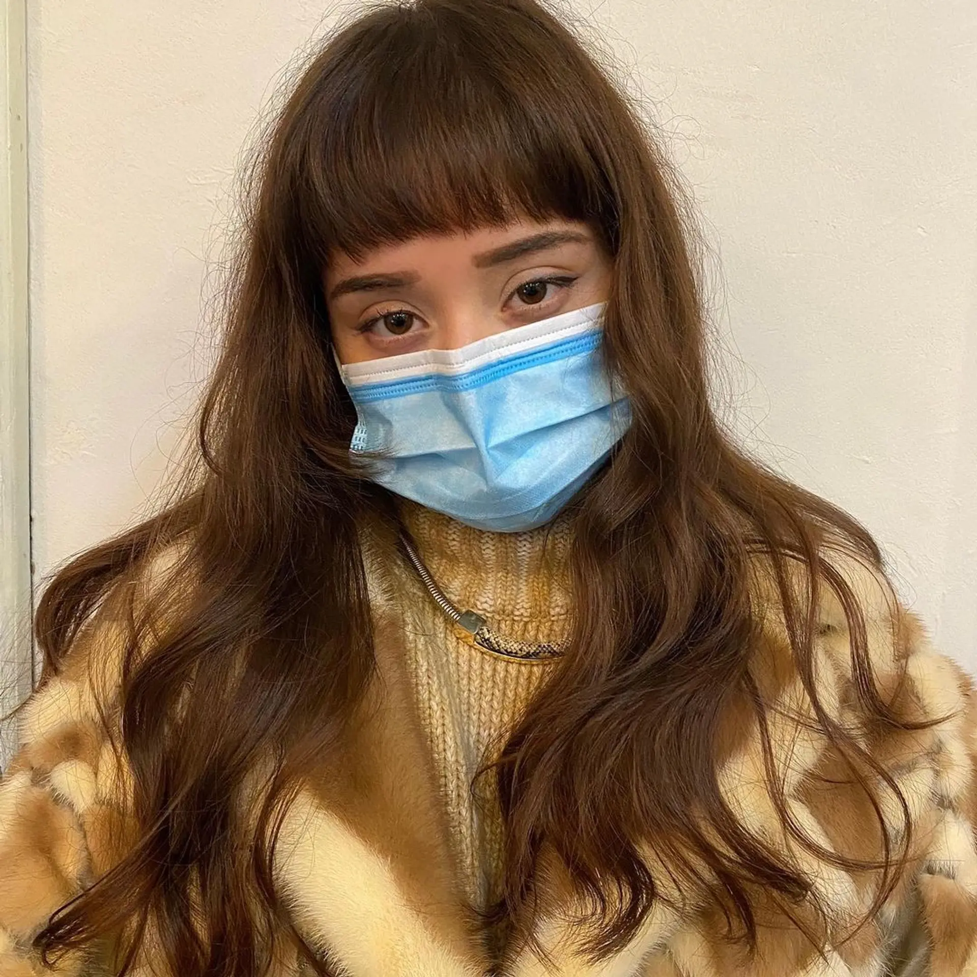 Long chestnut brown wavy hair with micro bangs. The hairstyle features natural, loose waves and layers that add dimension and movement by Coco. 2