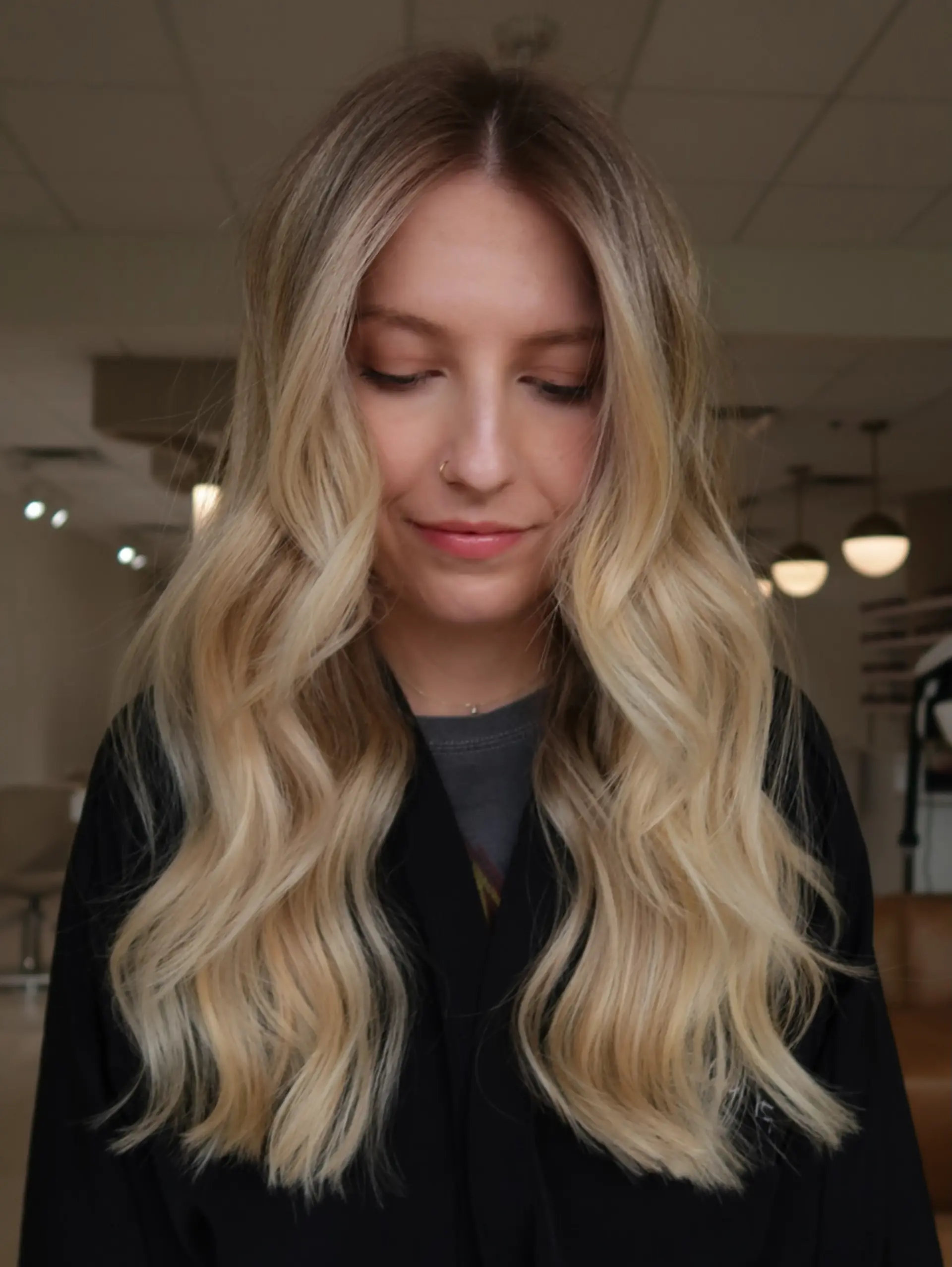 Long blonde balayage with seamless rooted dimension, styled into loose, flowing waves. 1