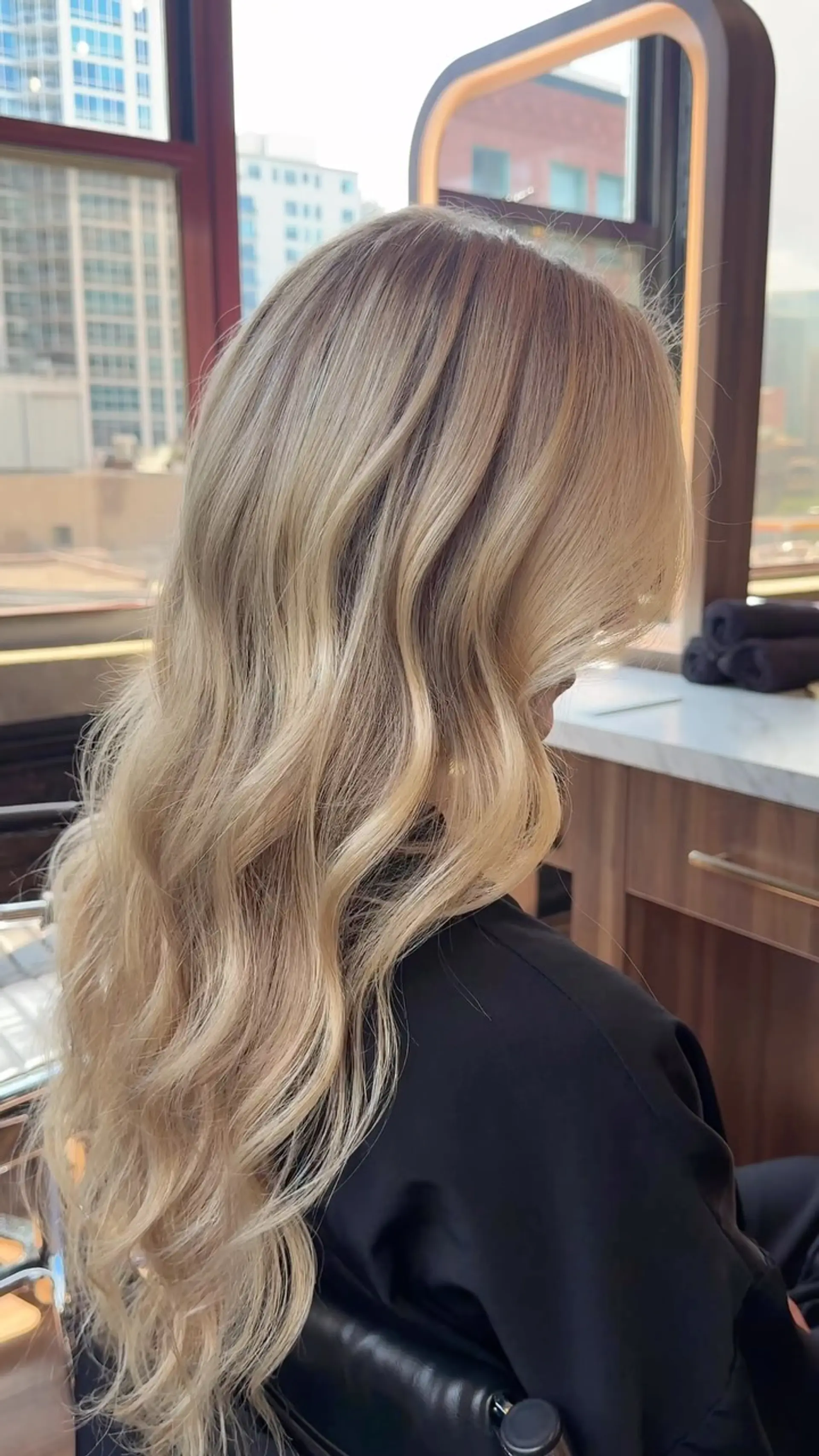 Long butter blonde hair featuring seamless dimensional balayage styled in soft, flowing waves. 1