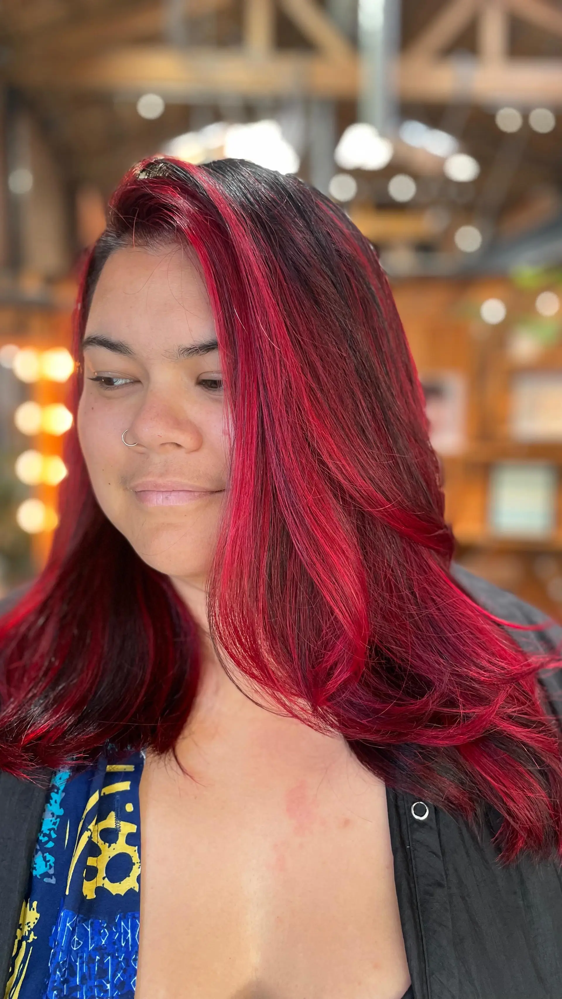 Vibrant fire-engine red hair color over deep dark roots, styled into a sleek and voluminous layered blowout. 1
