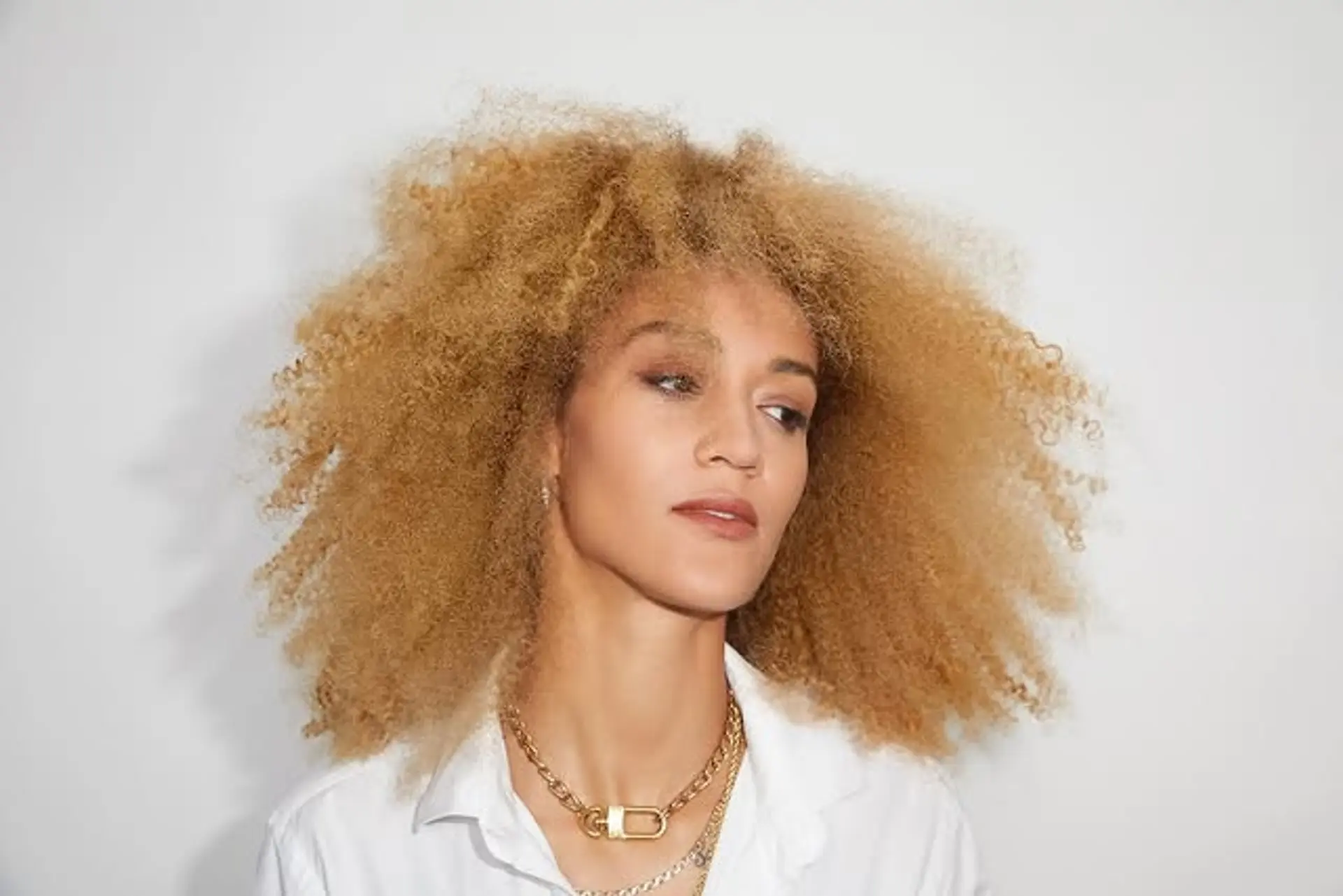 Voluminous afro with defined curls in a blonde color. 1